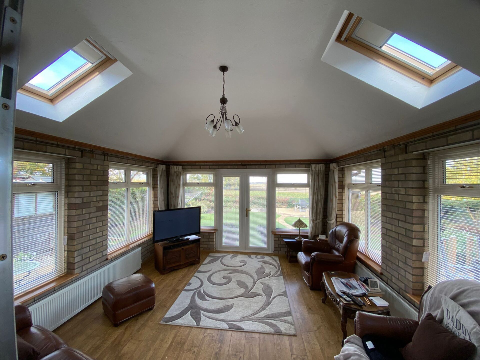 A living room with a lot of windows and a flat screen tv.