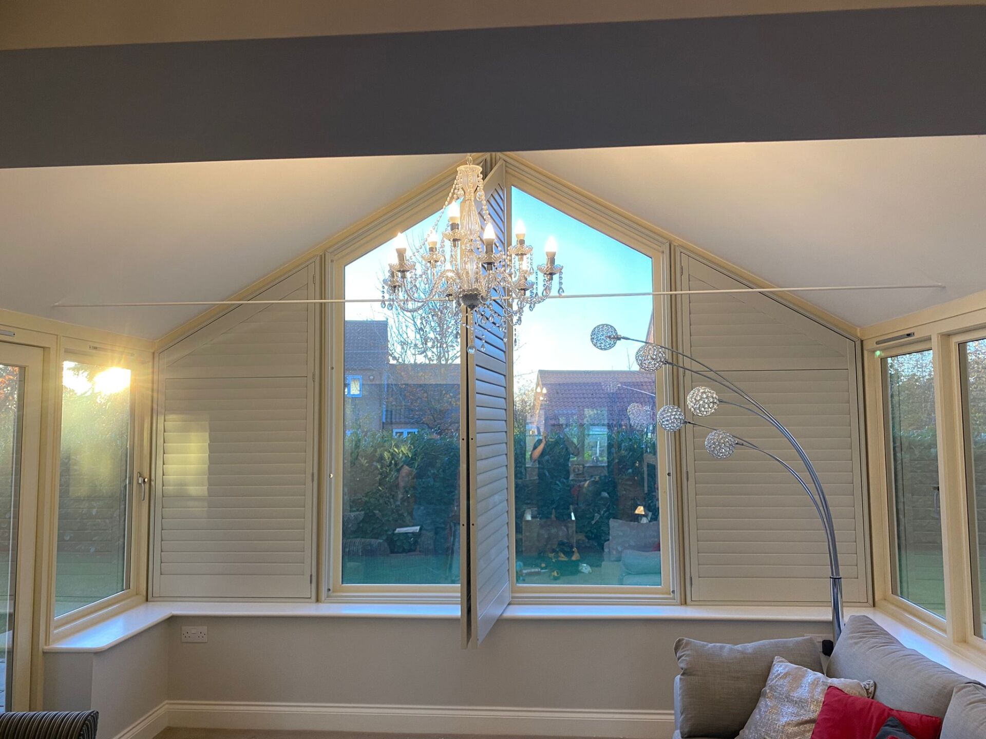 A living room with a chandelier hanging from the ceiling and a large window.