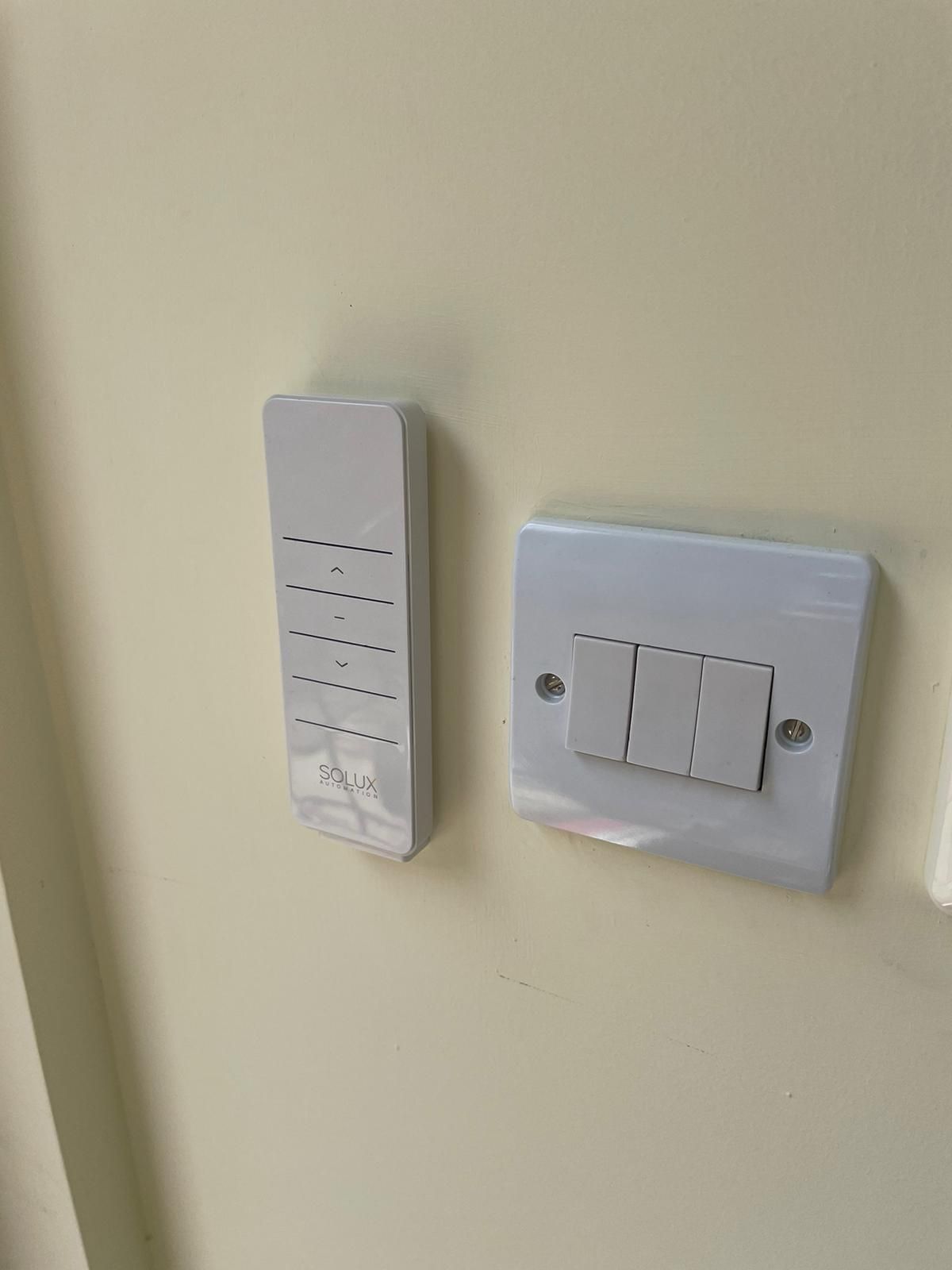 There is a remote control and a light switch on the wall.