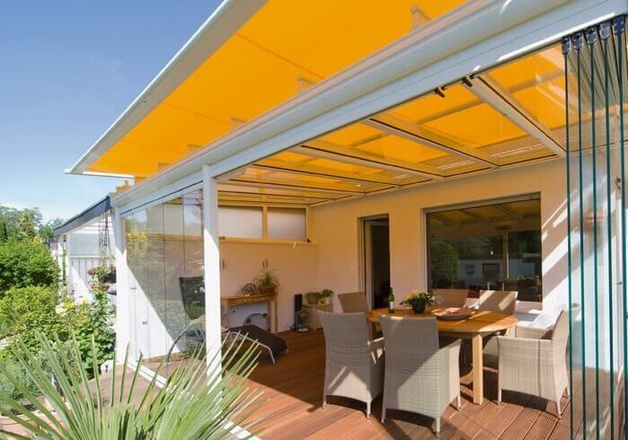 A patio with a yellow awning and a table and chairs