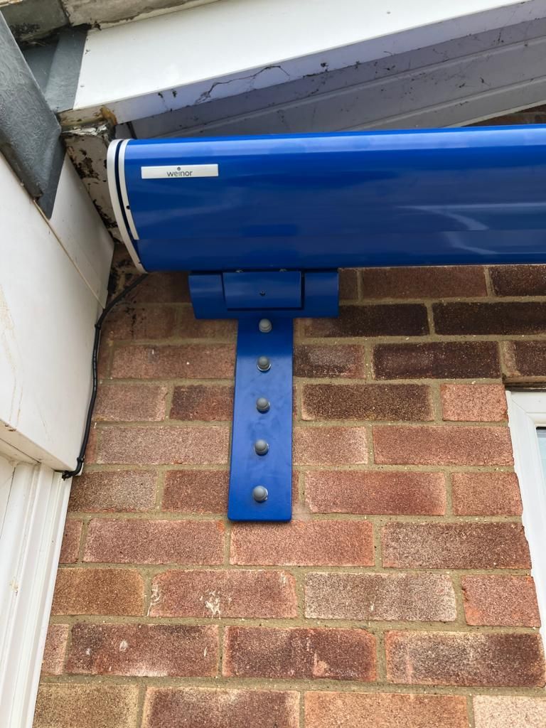 A blue awning is attached to a brick wall.
