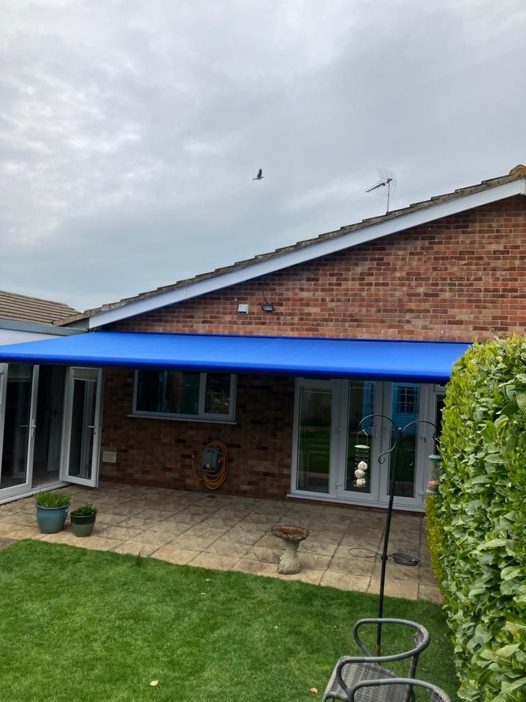 A blue awning is on the side of a brick house.