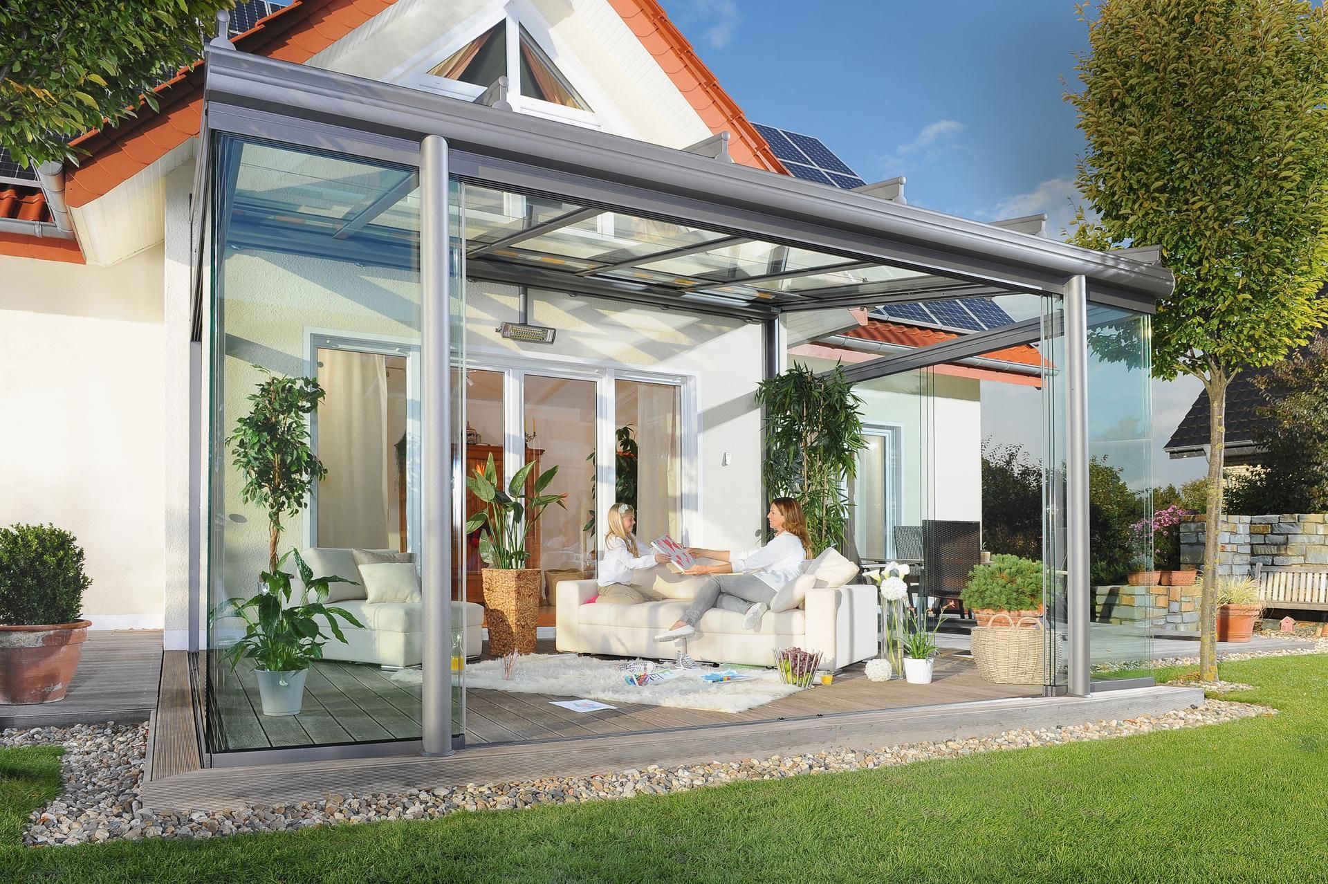 A couple of people are sitting on a couch under a glass roof.