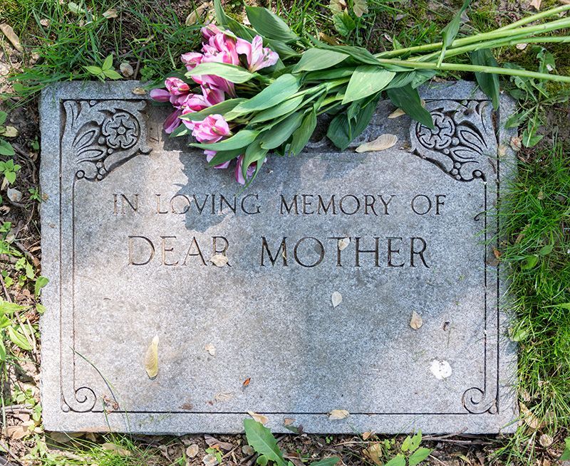 A gravestone for a dear mother with flowers on it