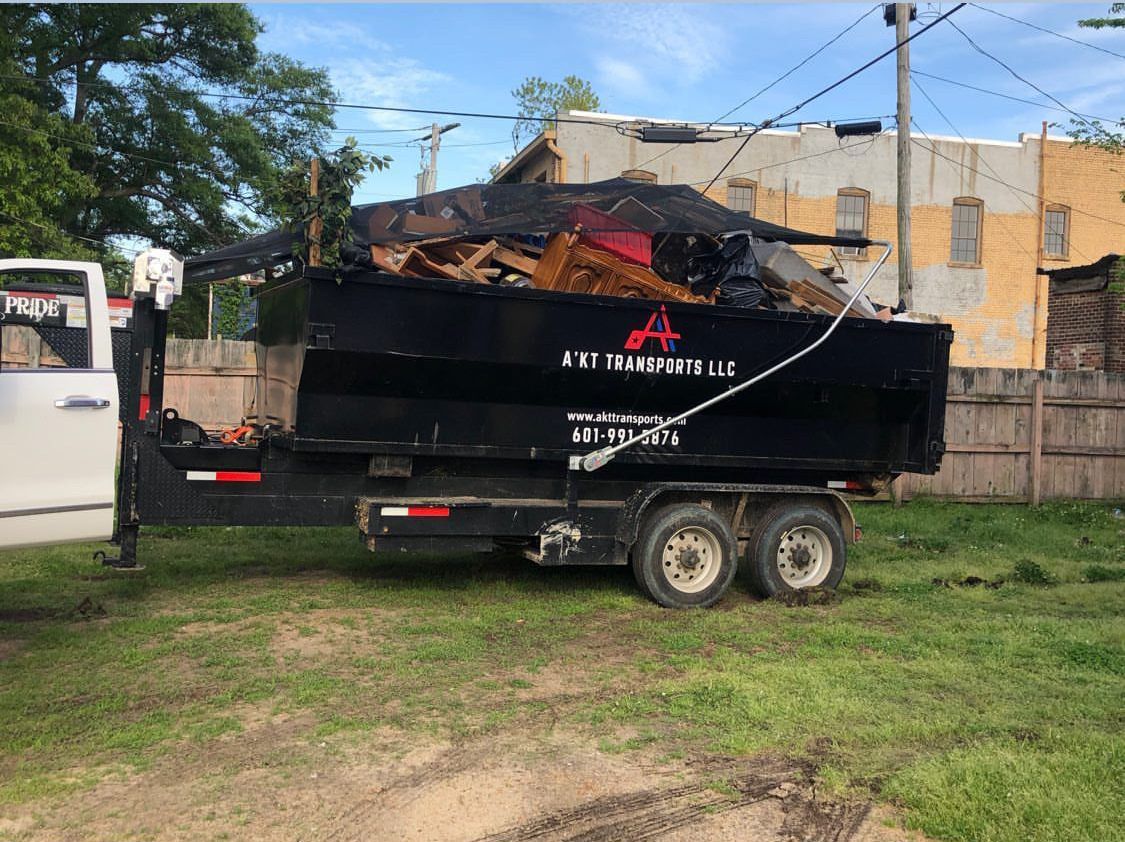 A dumpster is sitting on top of a trailer in a grassy field.