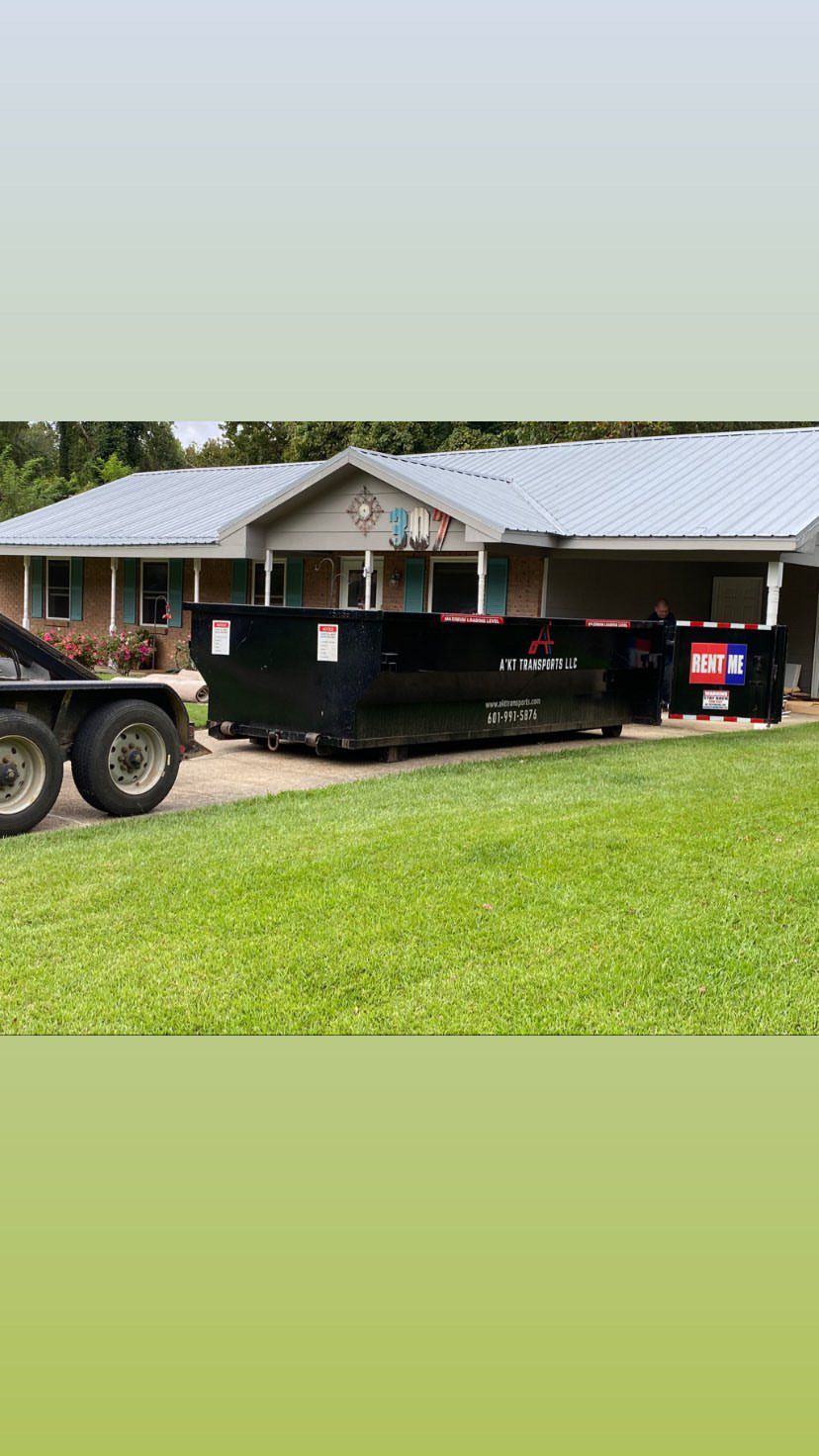 A row of dumpsters are parked in a gravel lot.