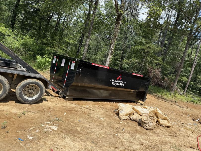A dumpster is sitting on the ground next to a truck.