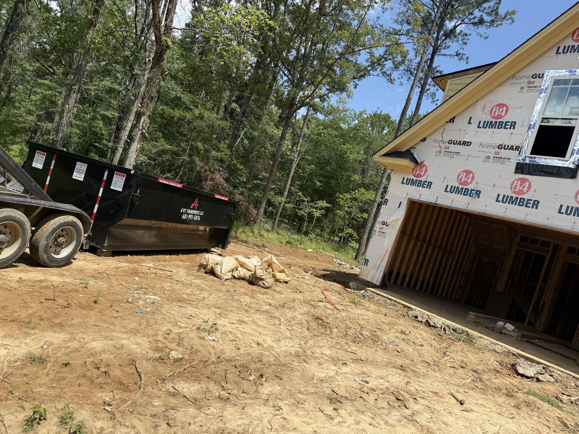 A dumpster is parked in front of a house under construction.