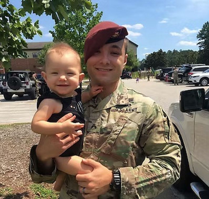 Sam Kensinger holding a smiling baby outdoors