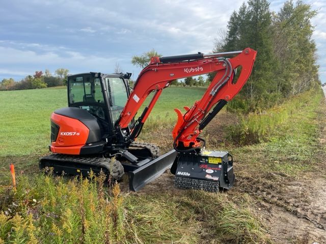 A red and black excavator is parked on the side of a dirt road.
