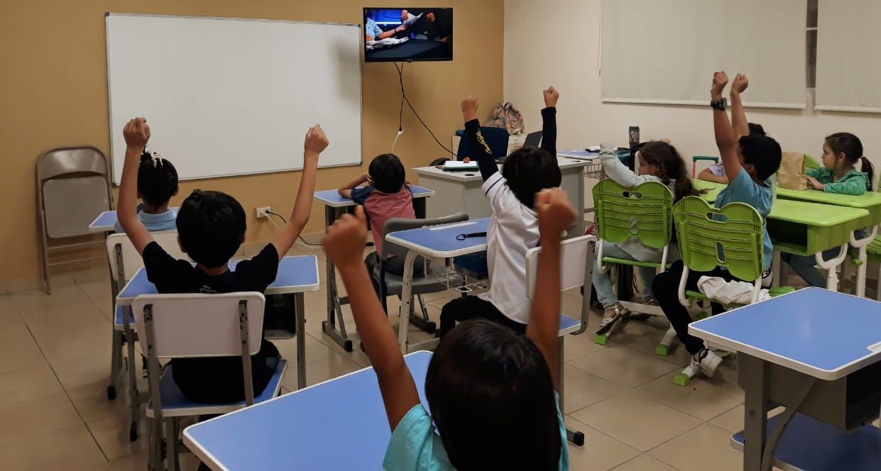Clase participativa con estudiantes levantando la mano en CEI Montessori 