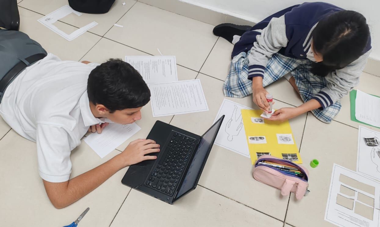 Niños trabajando en equipo con laptops y material escolar en CEI Montessori 