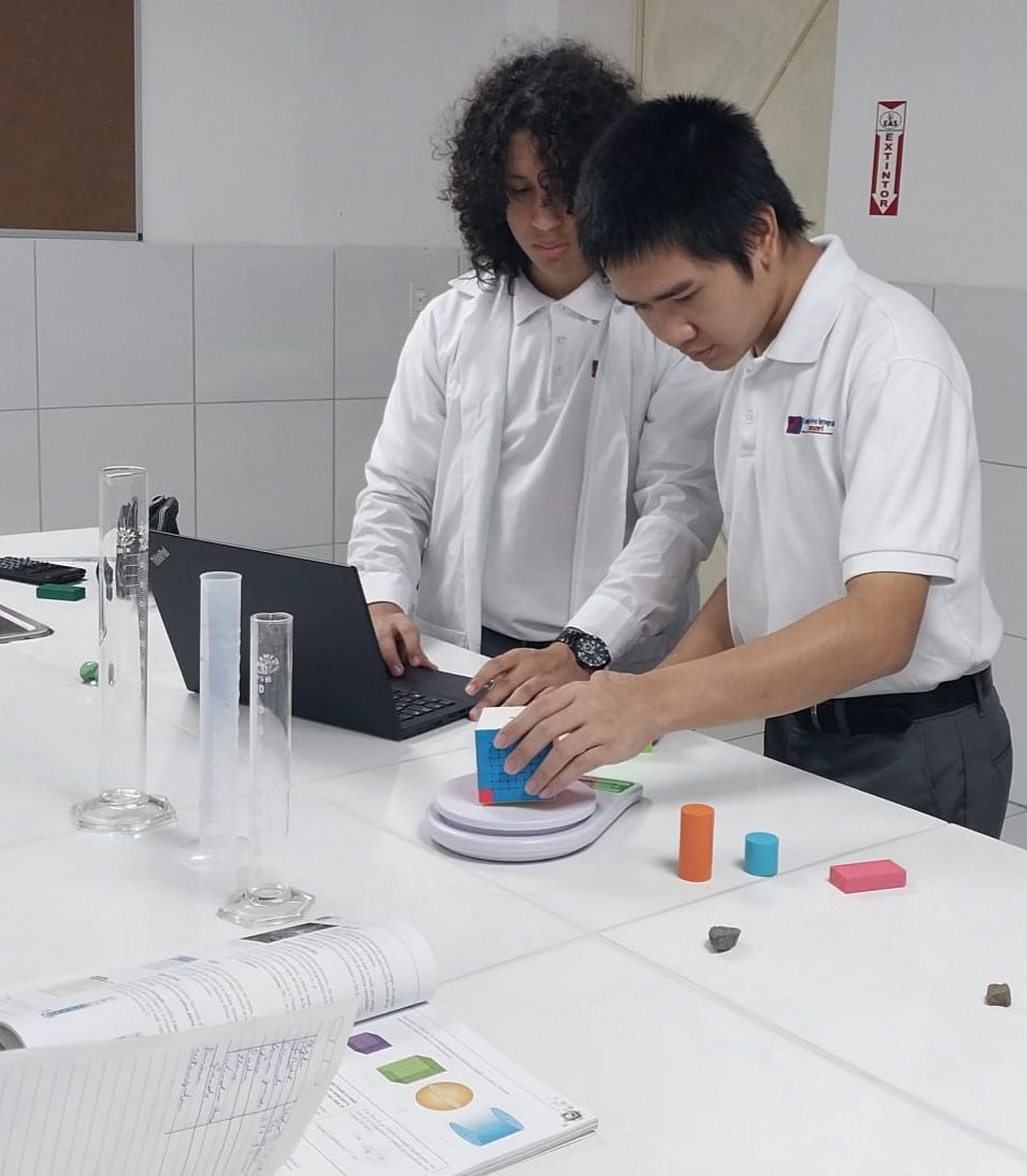 Estudiantes realizando experimento con cilindros y líquidos en clase de ciencias, CEI Montessori