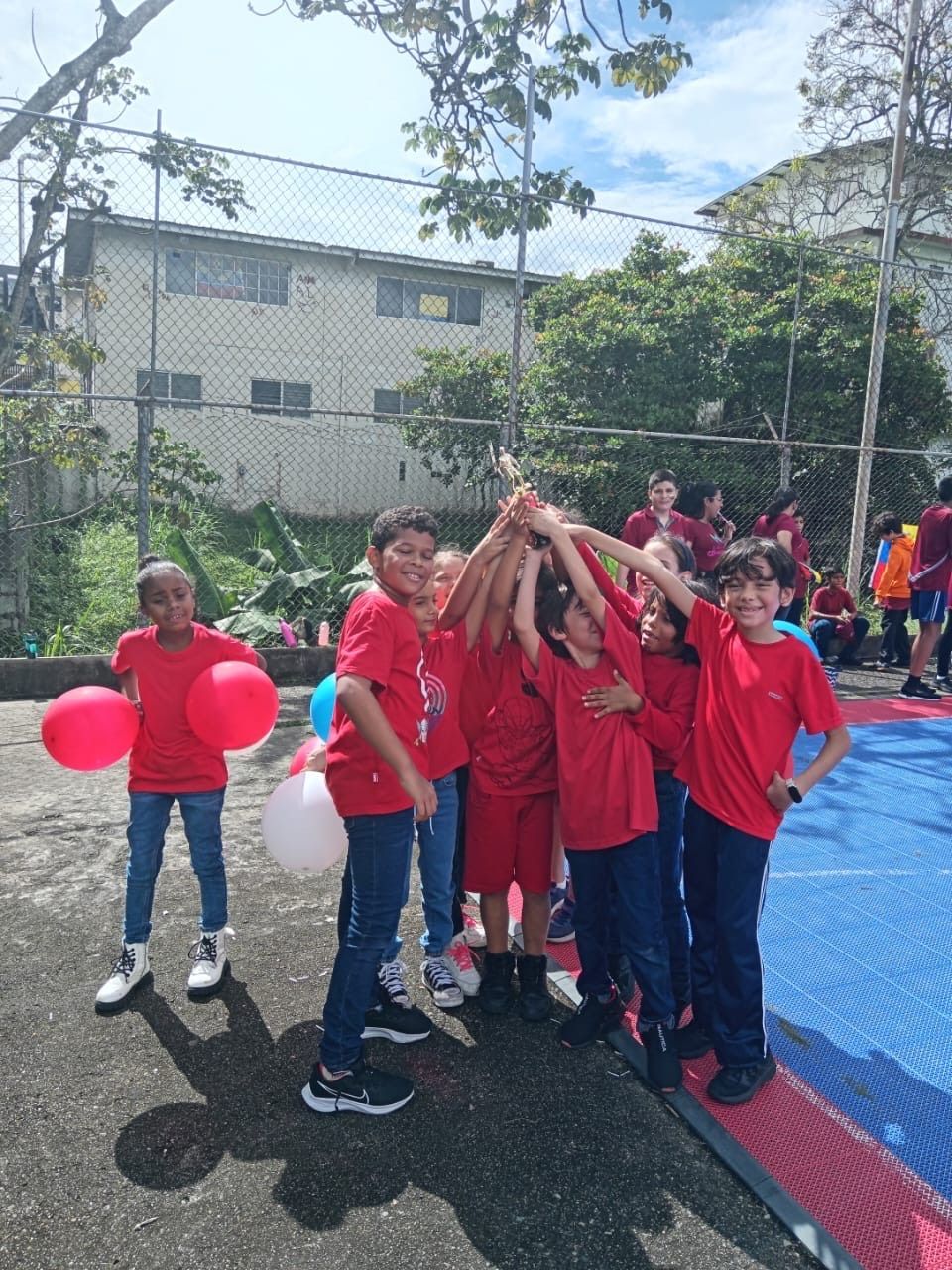 Celebración escolar con estudiantes vestidos de rojo compartiendo alegría y compañerismo en CEI Montessori 