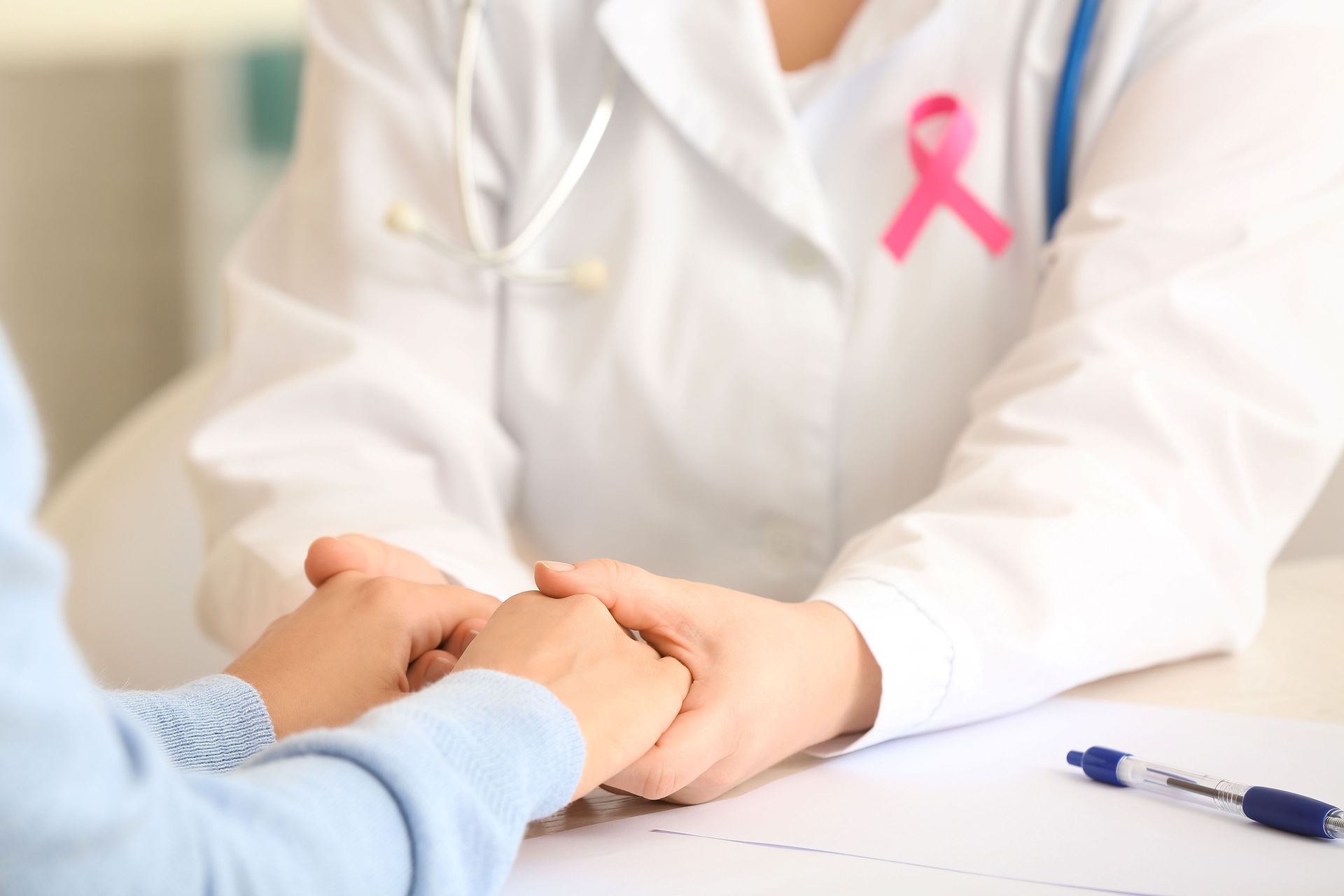 Cancer doctor holding patient’s hands during consultation showing compassionate oncology care.