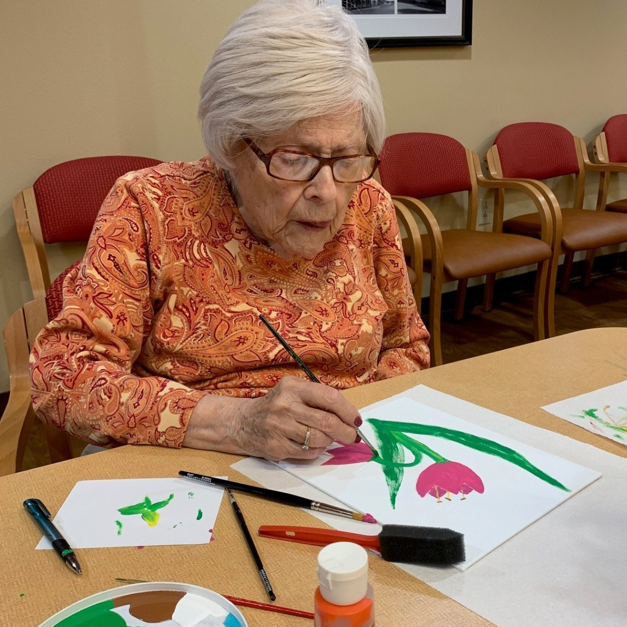 senior living resident painting flowers on paper