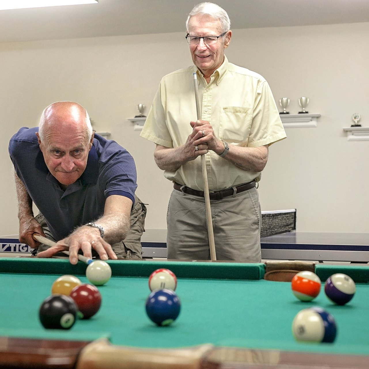 Two senior men shooting pool in the Billiards room at 55+ community