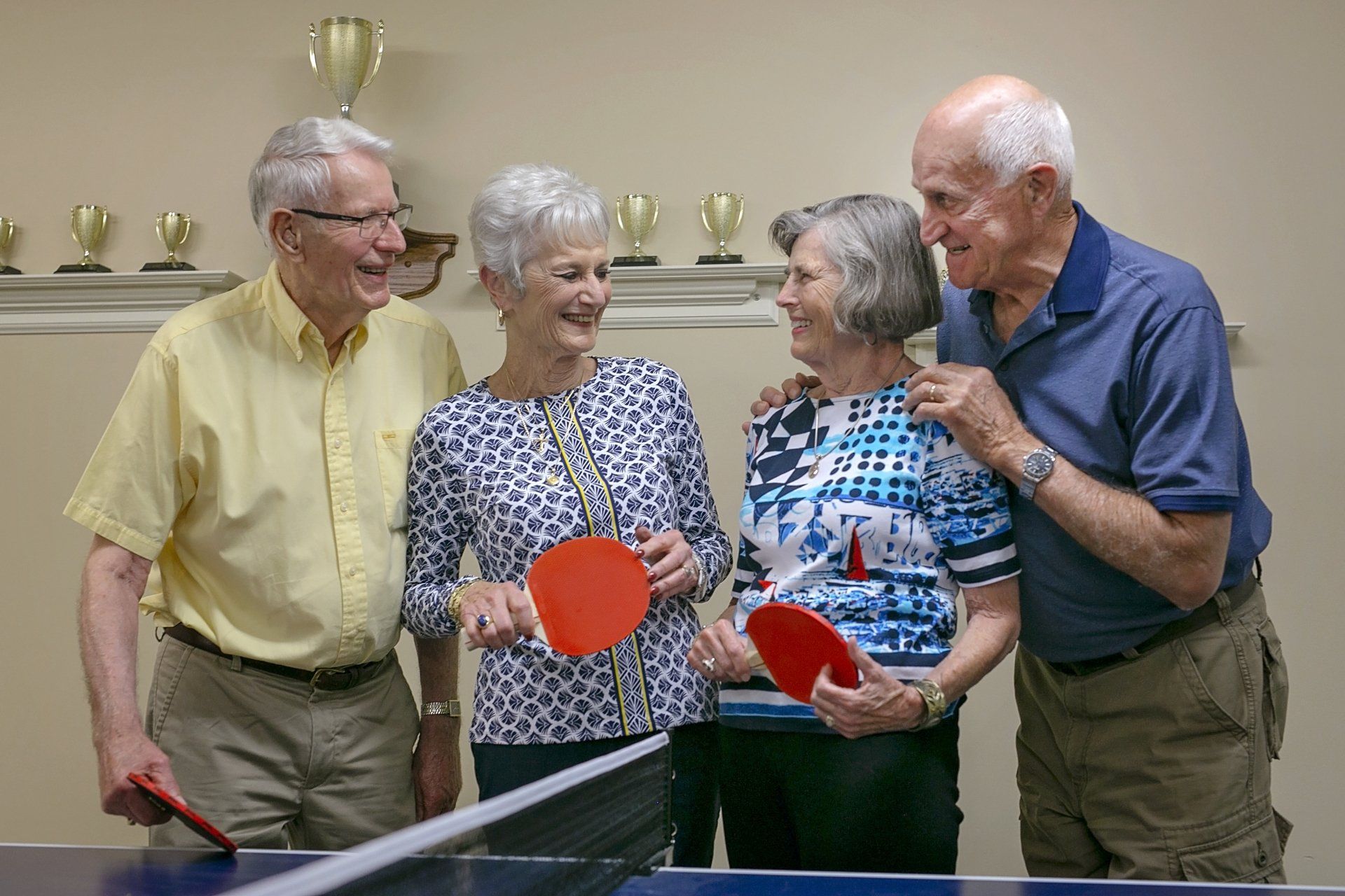 Active, senior living residents talking after playing a game of ping pong