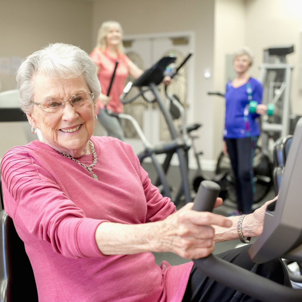 Retired lady exercising on a seated bike in the fitness center of 55+ community