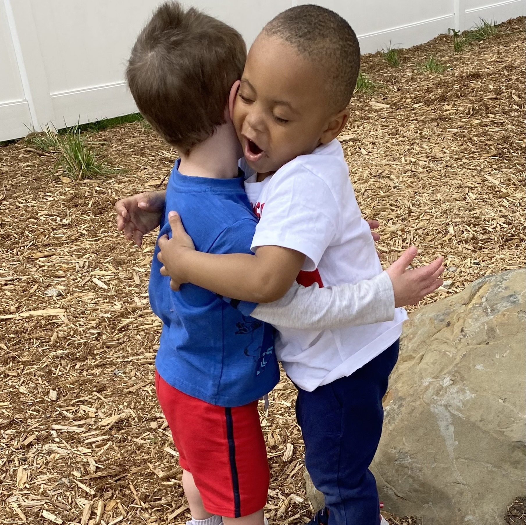 two little kids hugging each other on the playground outside of It Takes a Village Childcare Center