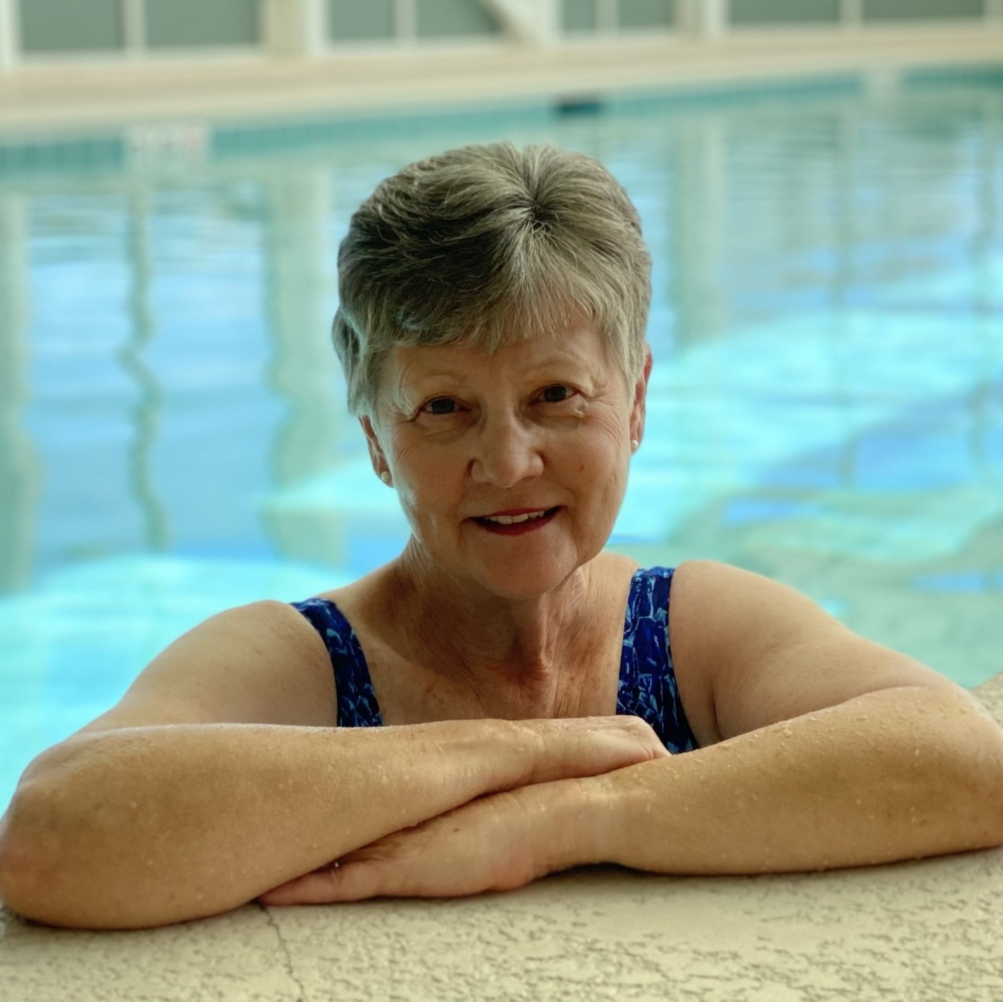 Active, retired lady sitting by the pool preparing for her wellness class at Landmark Commons