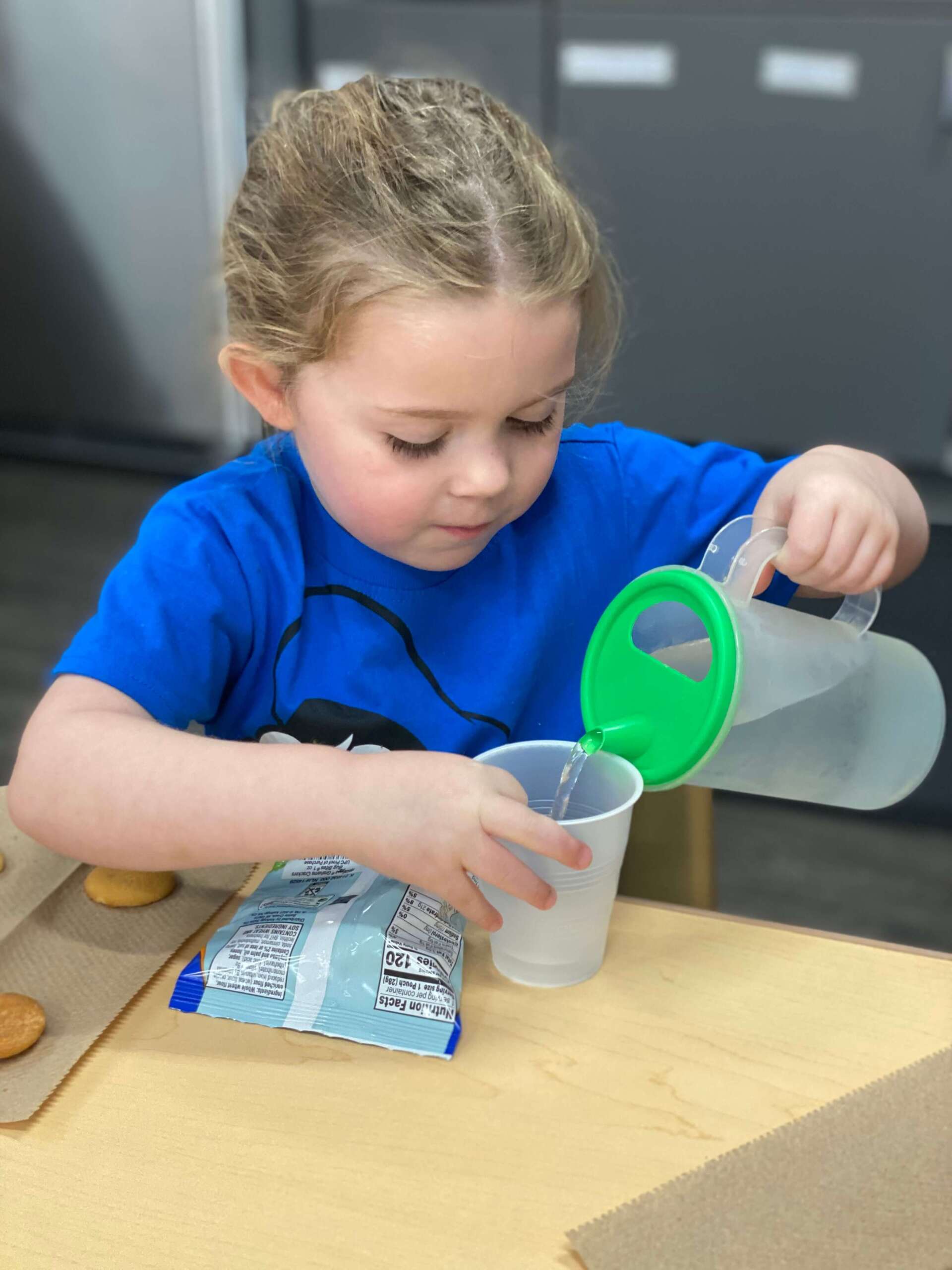 Child pouring water into a glass at snack time