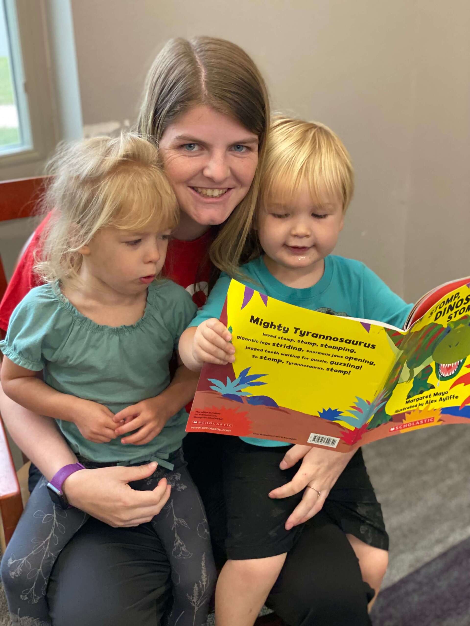 It Takes a Village Childcare employee reading a book with two kids