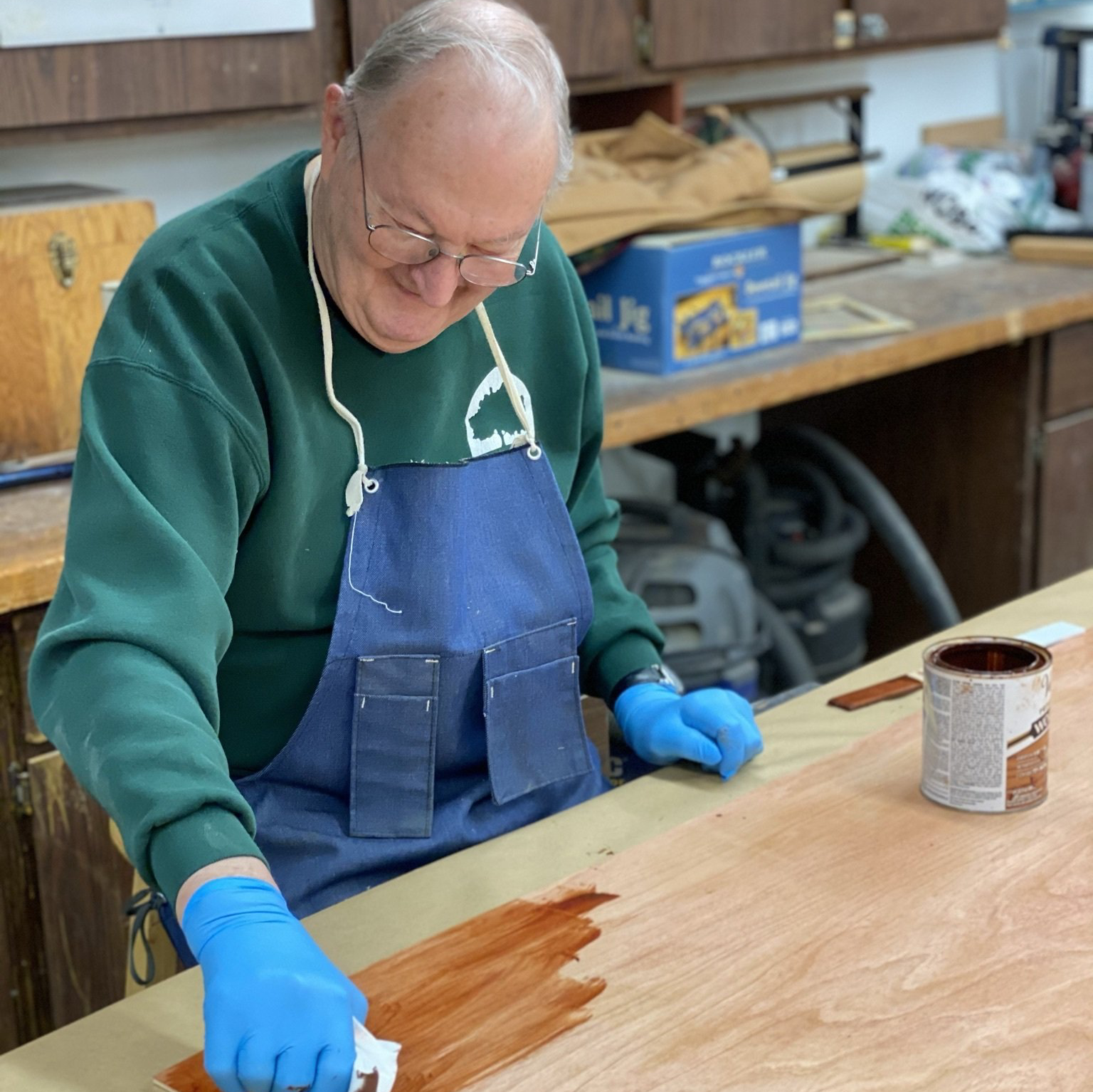 Man staining a handmade bookcase in the resident woodshop at Village Place