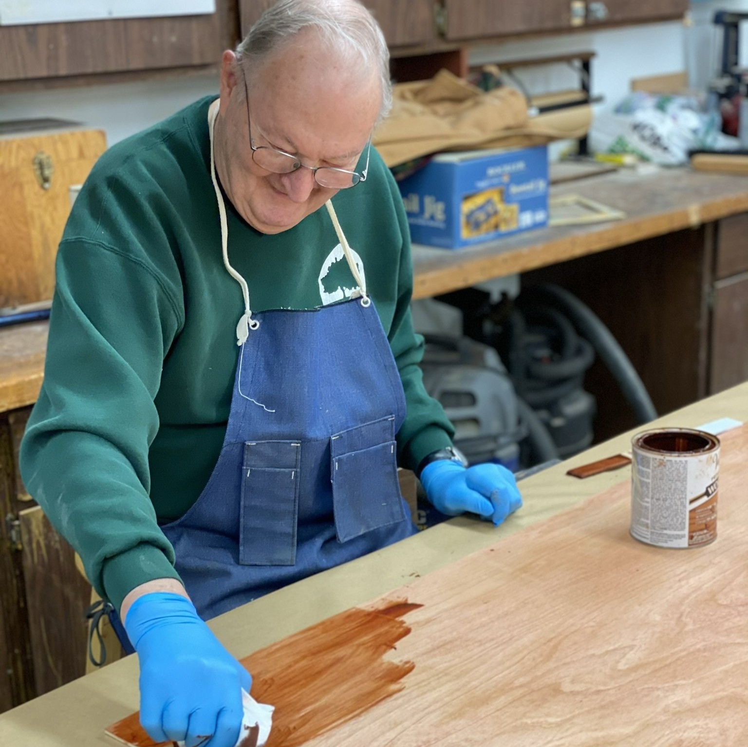 Man staining a handmade bookcase in the resident woodshop