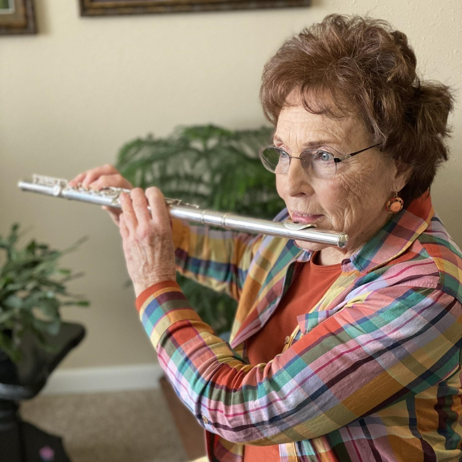 Retired lady playing music on her flute in her independent apartment