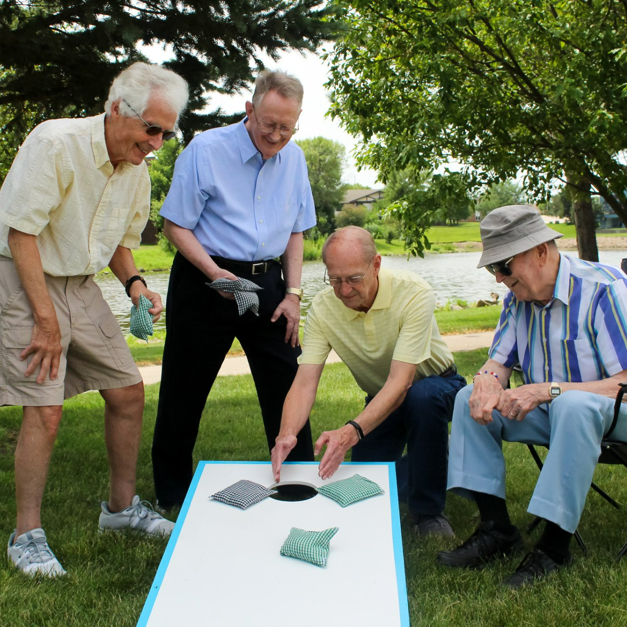 Group of retired men playing corn hole and contemplating the score