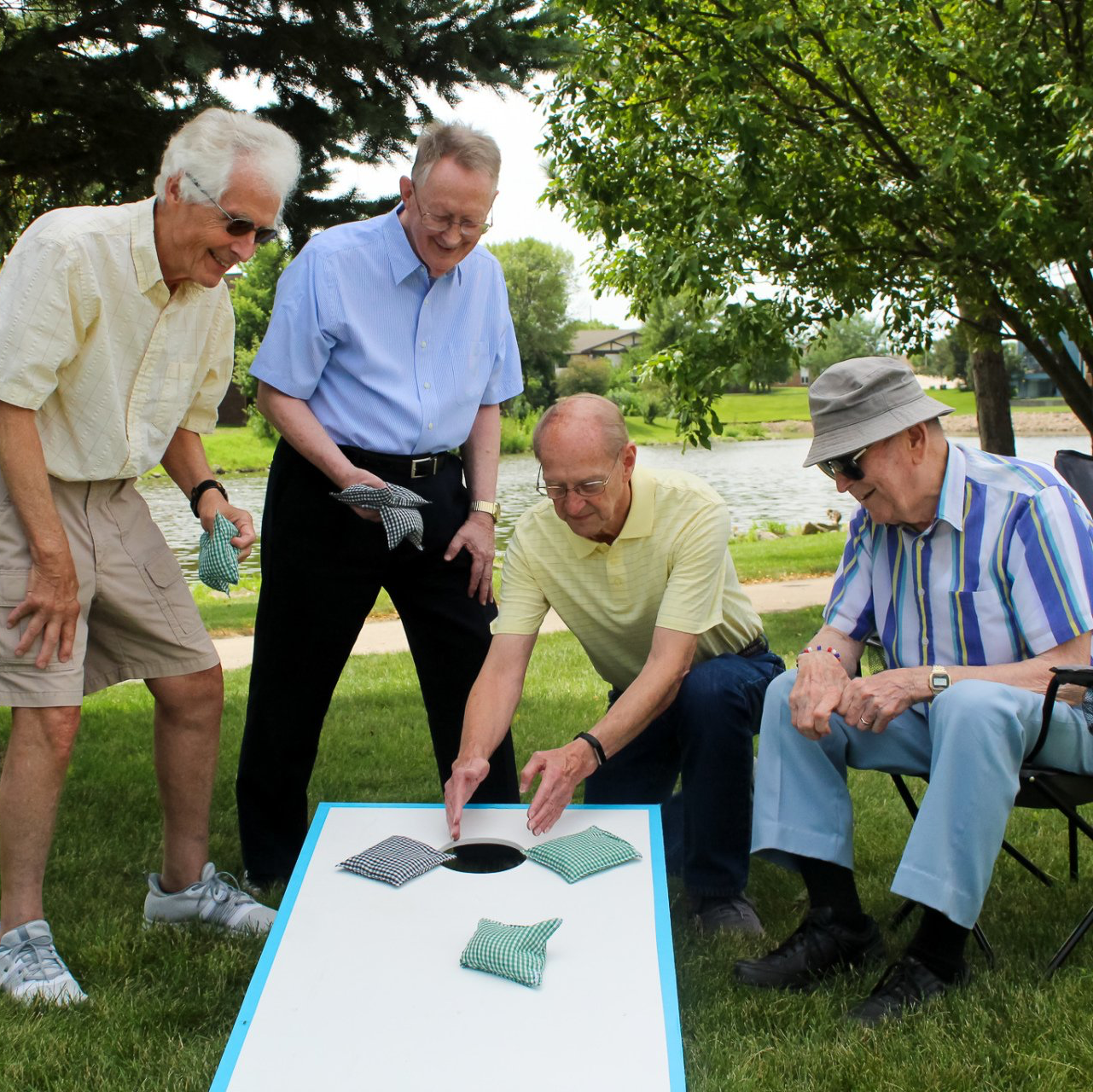 Group of retired men playing corn hole in the lawn of Friendship Village Retirement Community