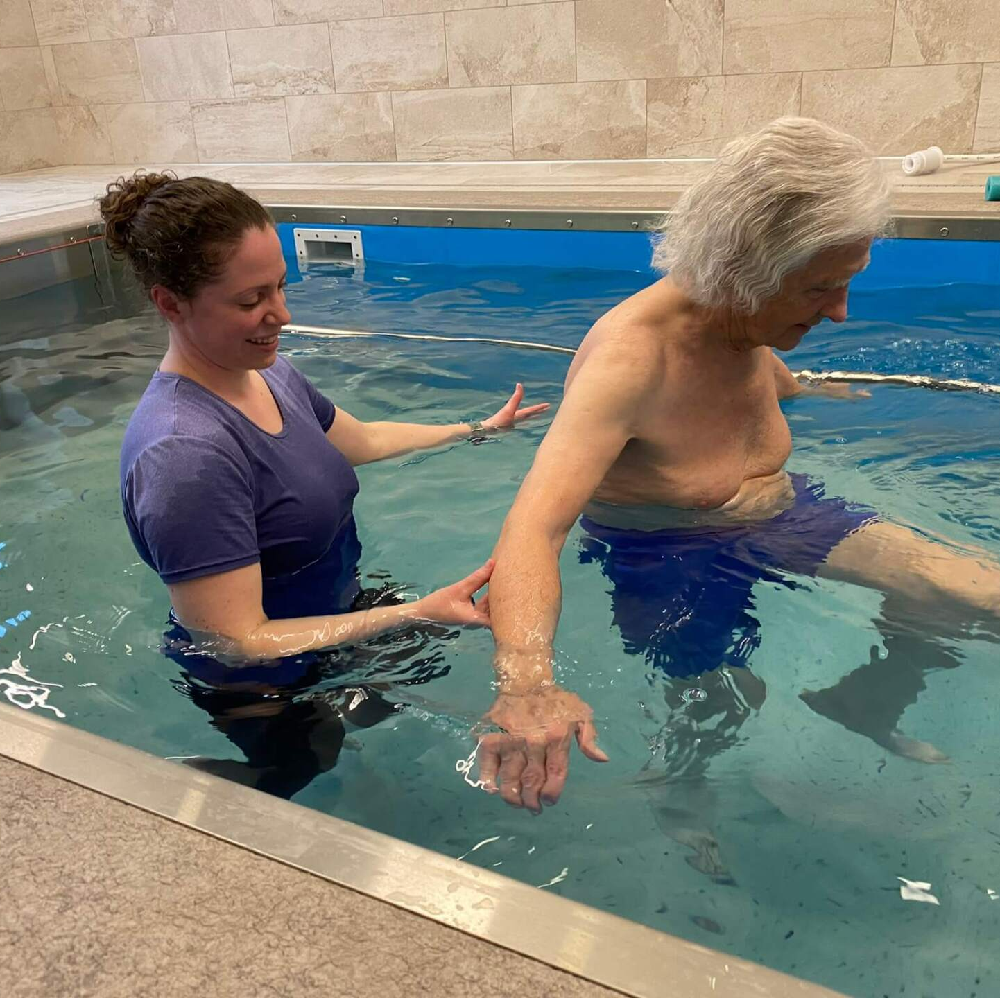 resident walking in hydro pool with physical therapist
