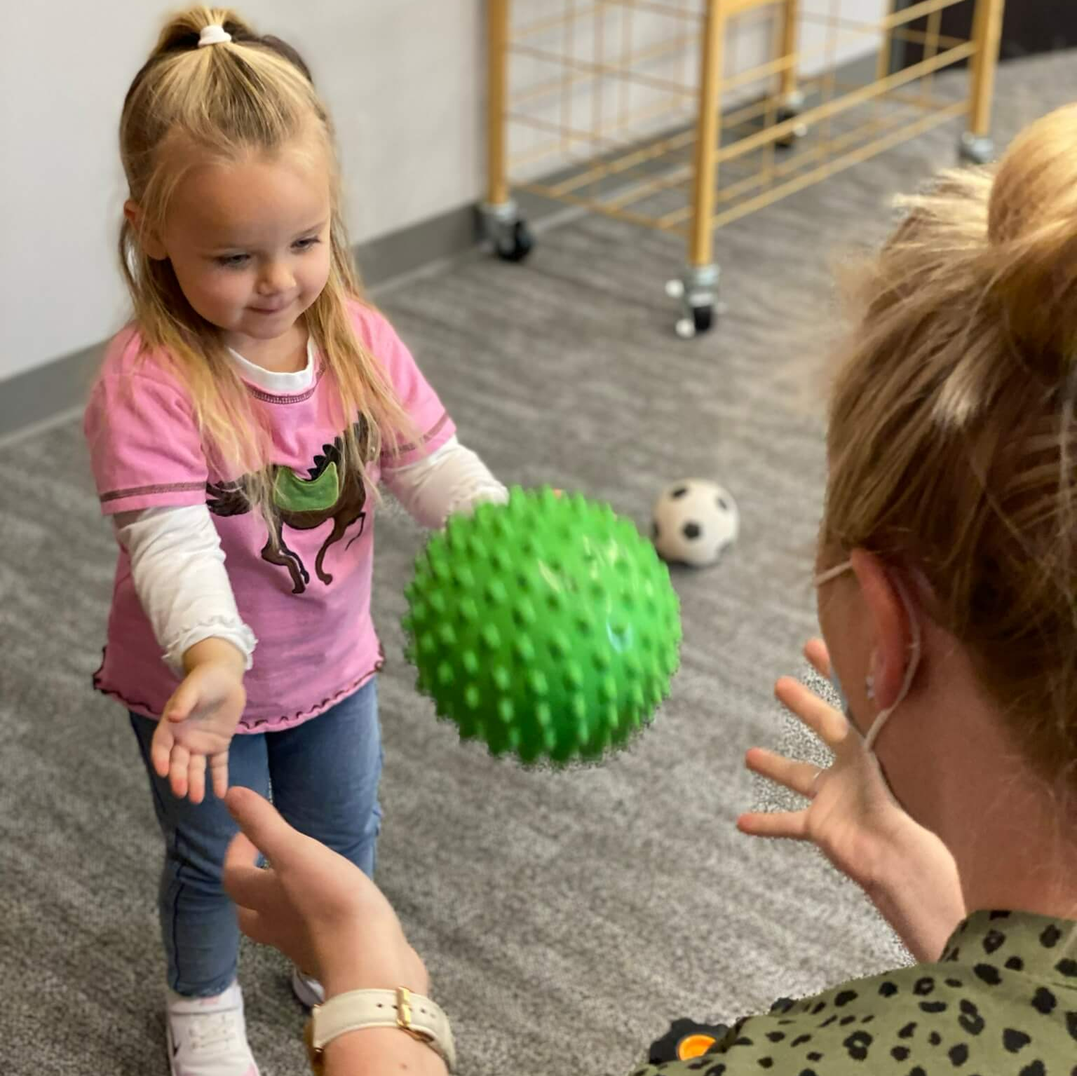 child playing catch with an Occupational Therapist in the playroom of It Takes a Village Childcare