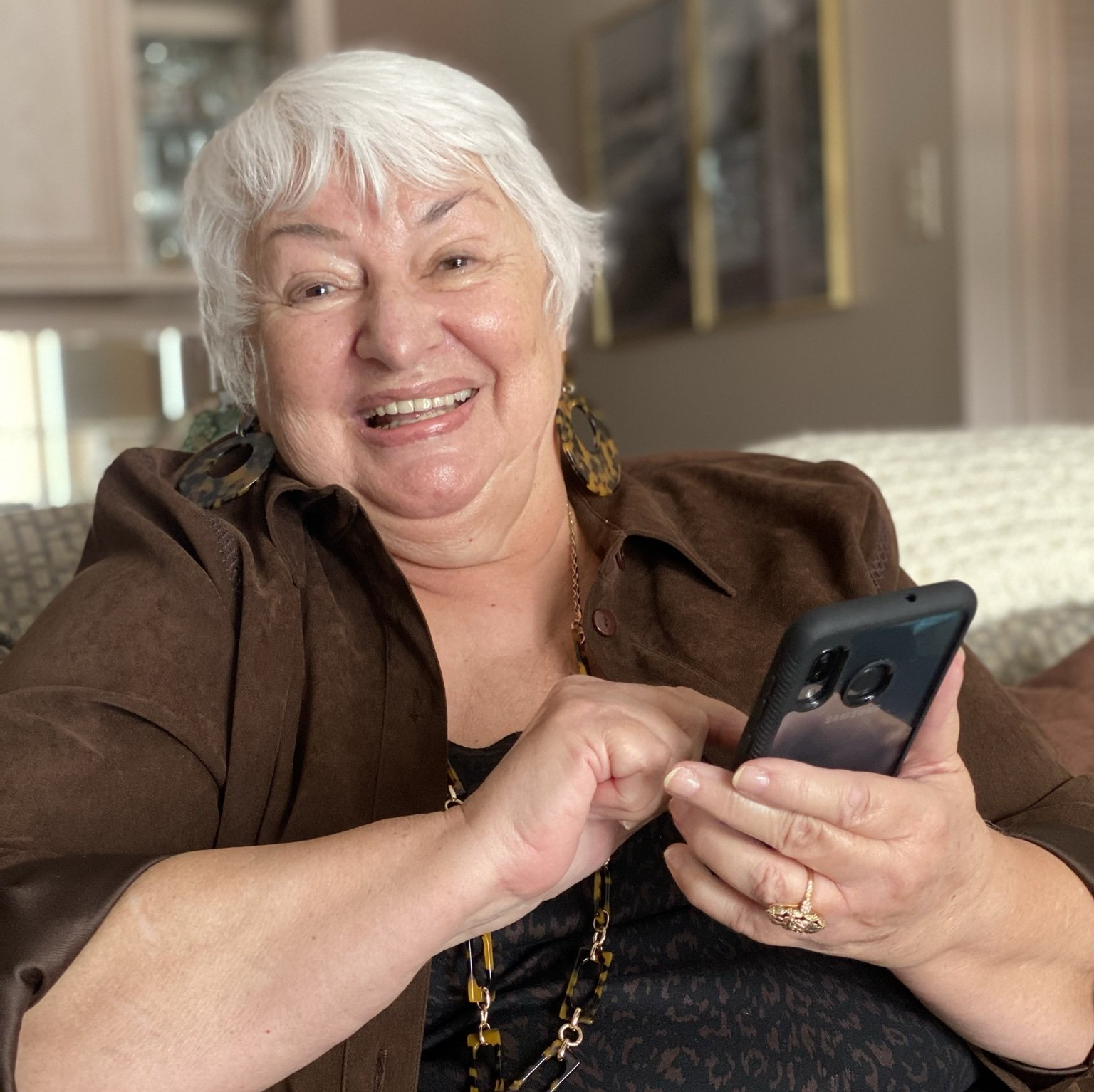 retired lady scrolling through her phone on the couch in her independent living apartment