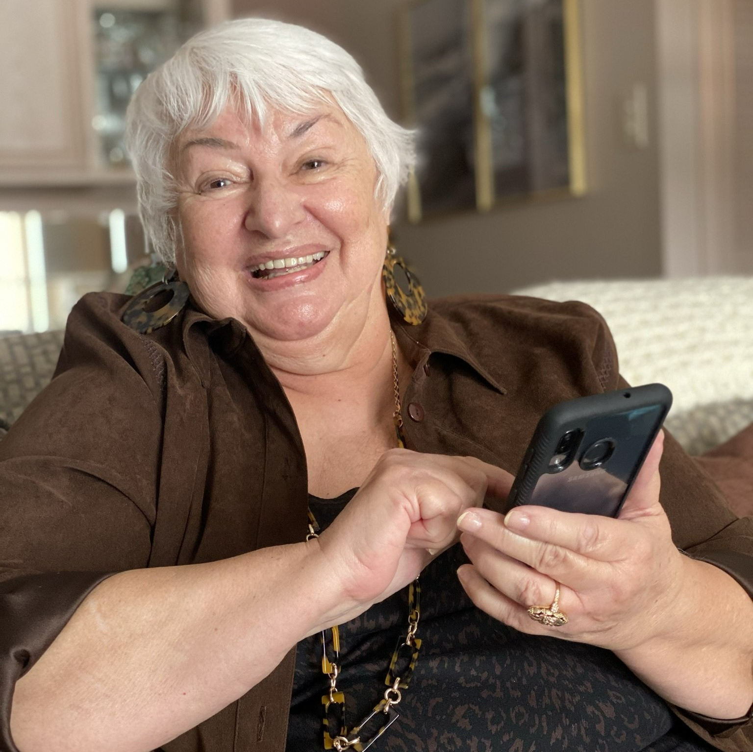 retired lady scrolling through her phone on the couch in her independent living apartment