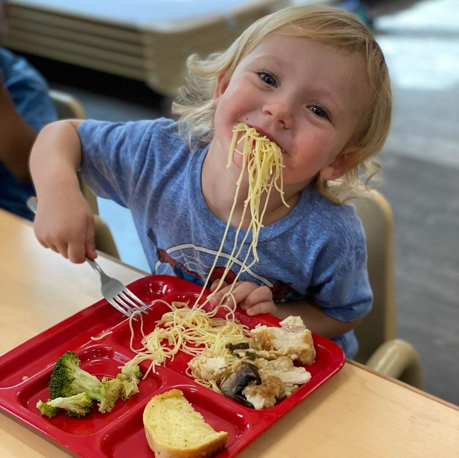 child eating with spaghetti hanging out of his mouth