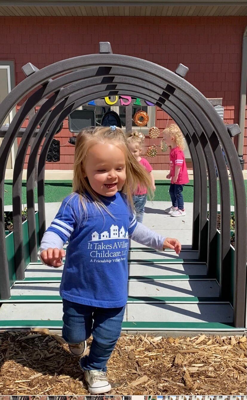 young girl running through a tunnel in the outdoor classroom at It Takes a Village Childcare
