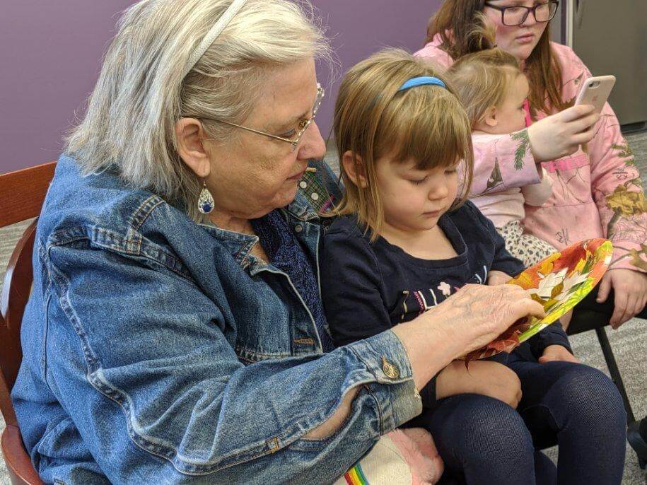 senior lady reading books to children at It Takes a Village Childcare