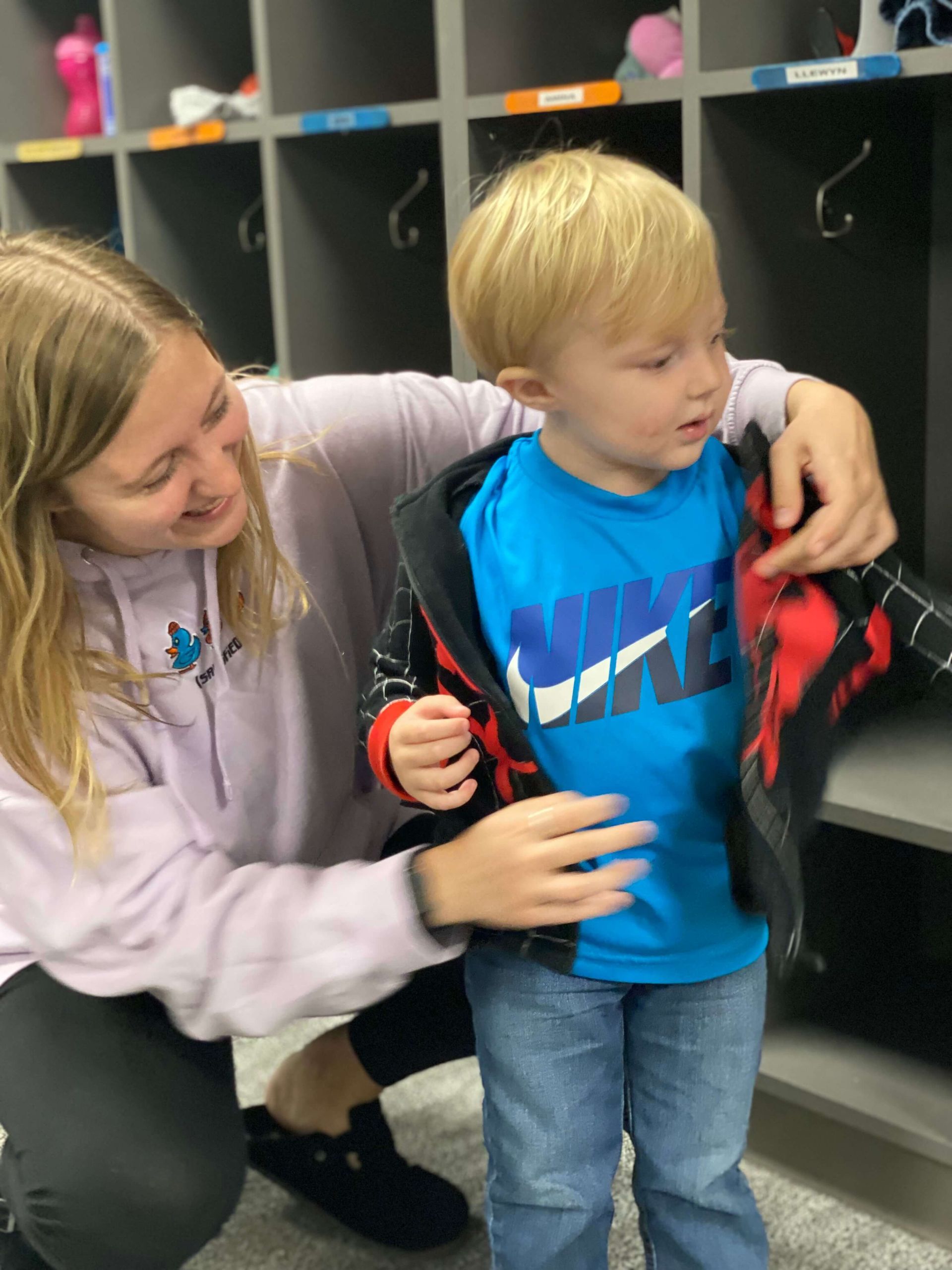 daycare provider helping child put on jacket