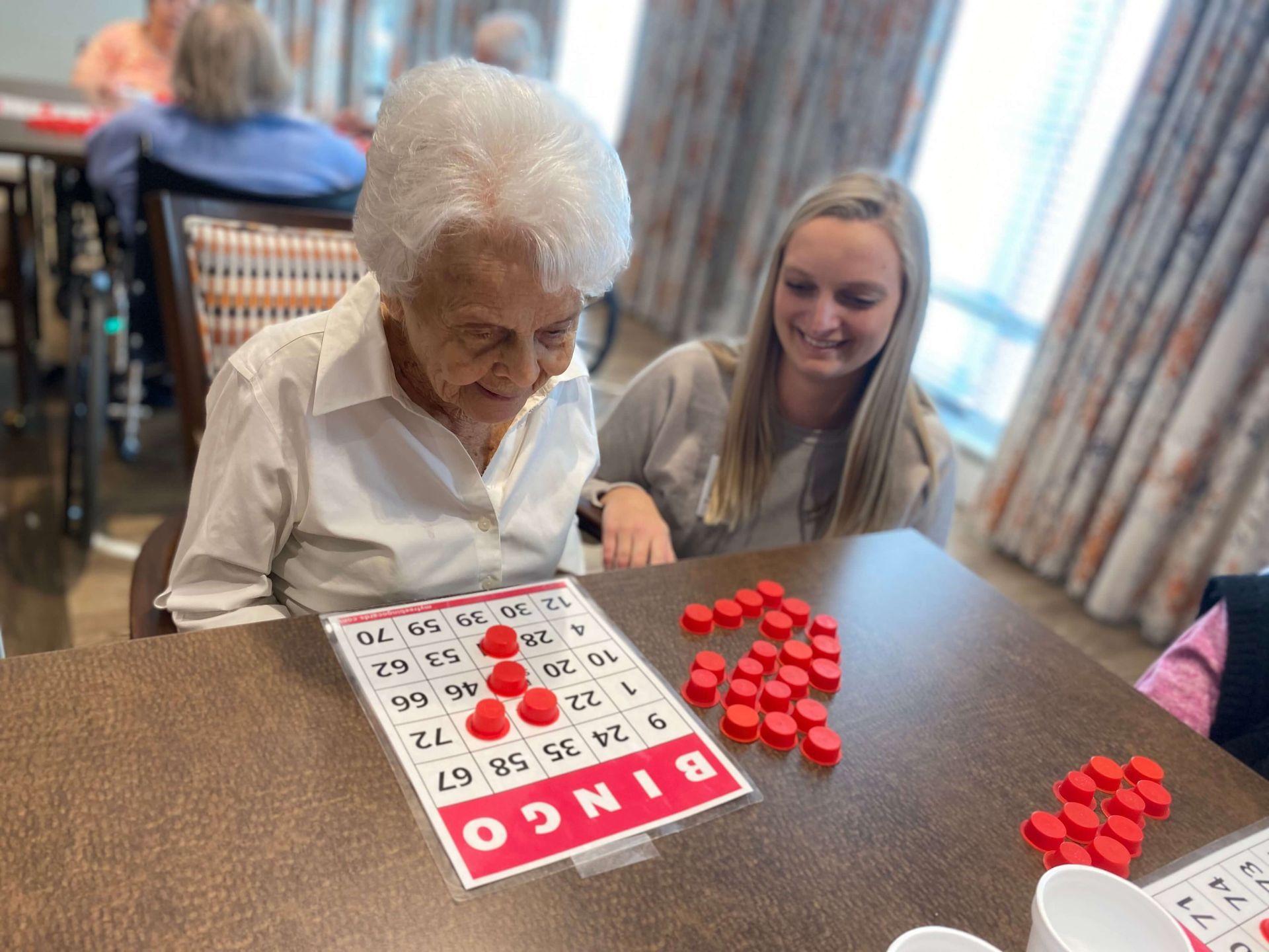 nursing home administrator assisting resident as they play bingo