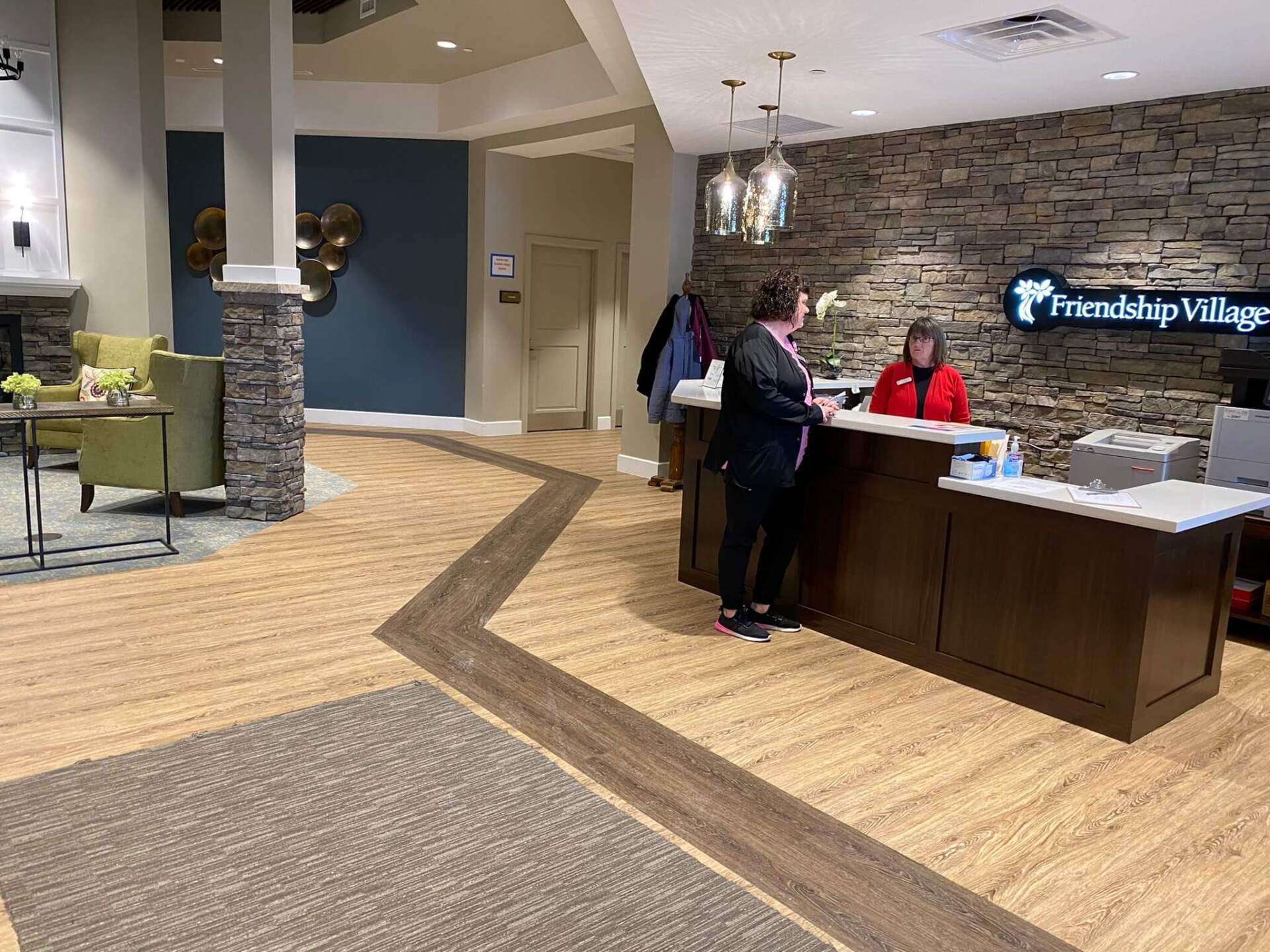 nurse and receptionist talking at the receptionist desk in the Wellspring Living lobby