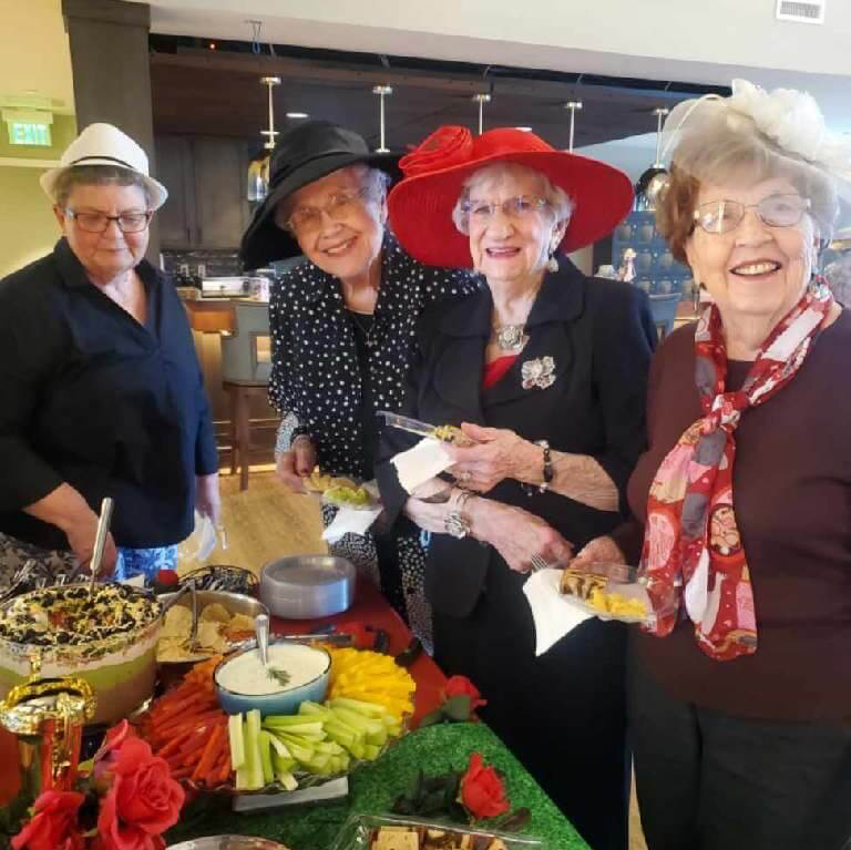 group of retired ladies wearing big hats and celebrating the Kentucky Derby with a spread of food