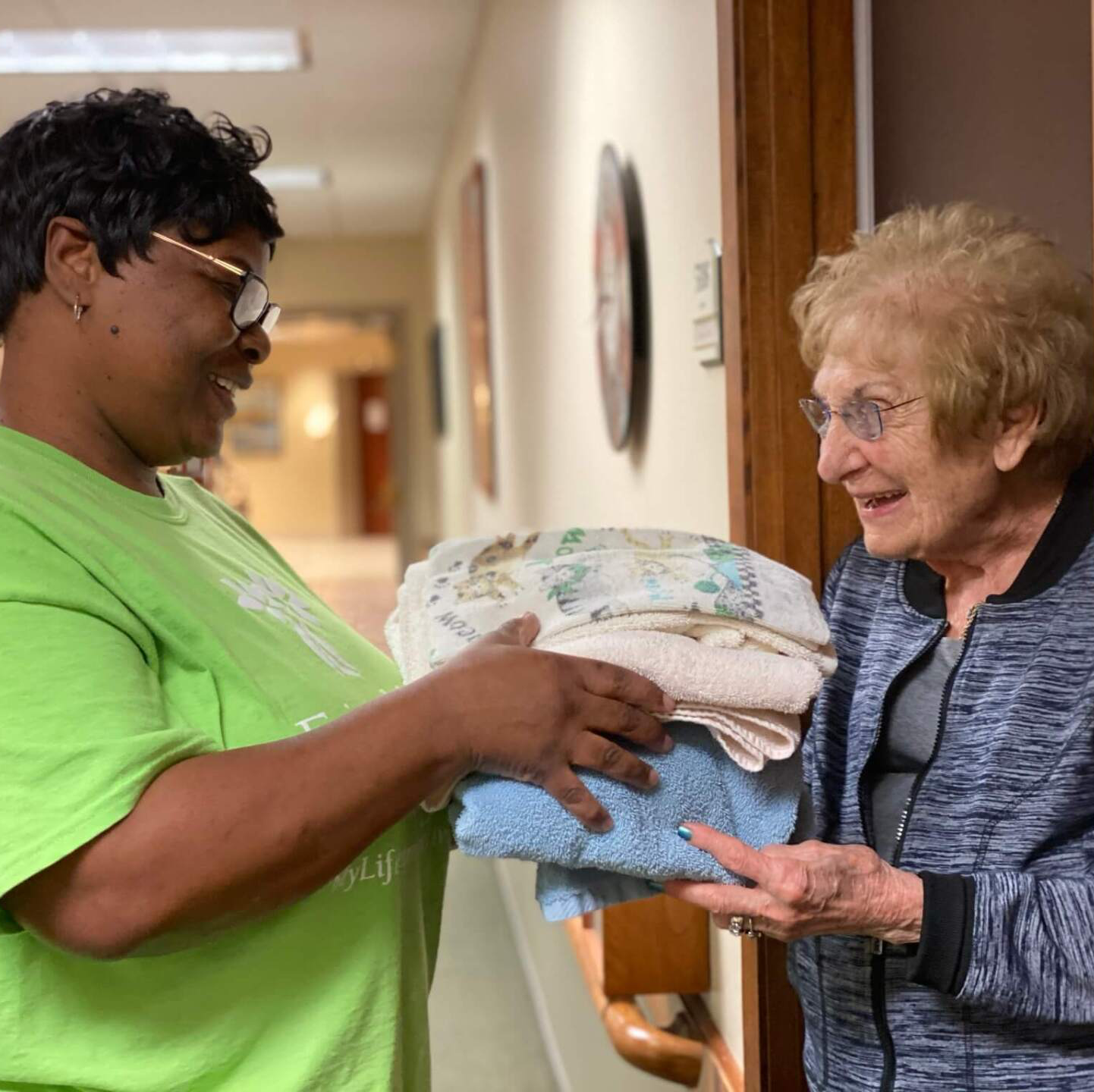 Housekeeper delivering clean towels to an independent living residents door step
