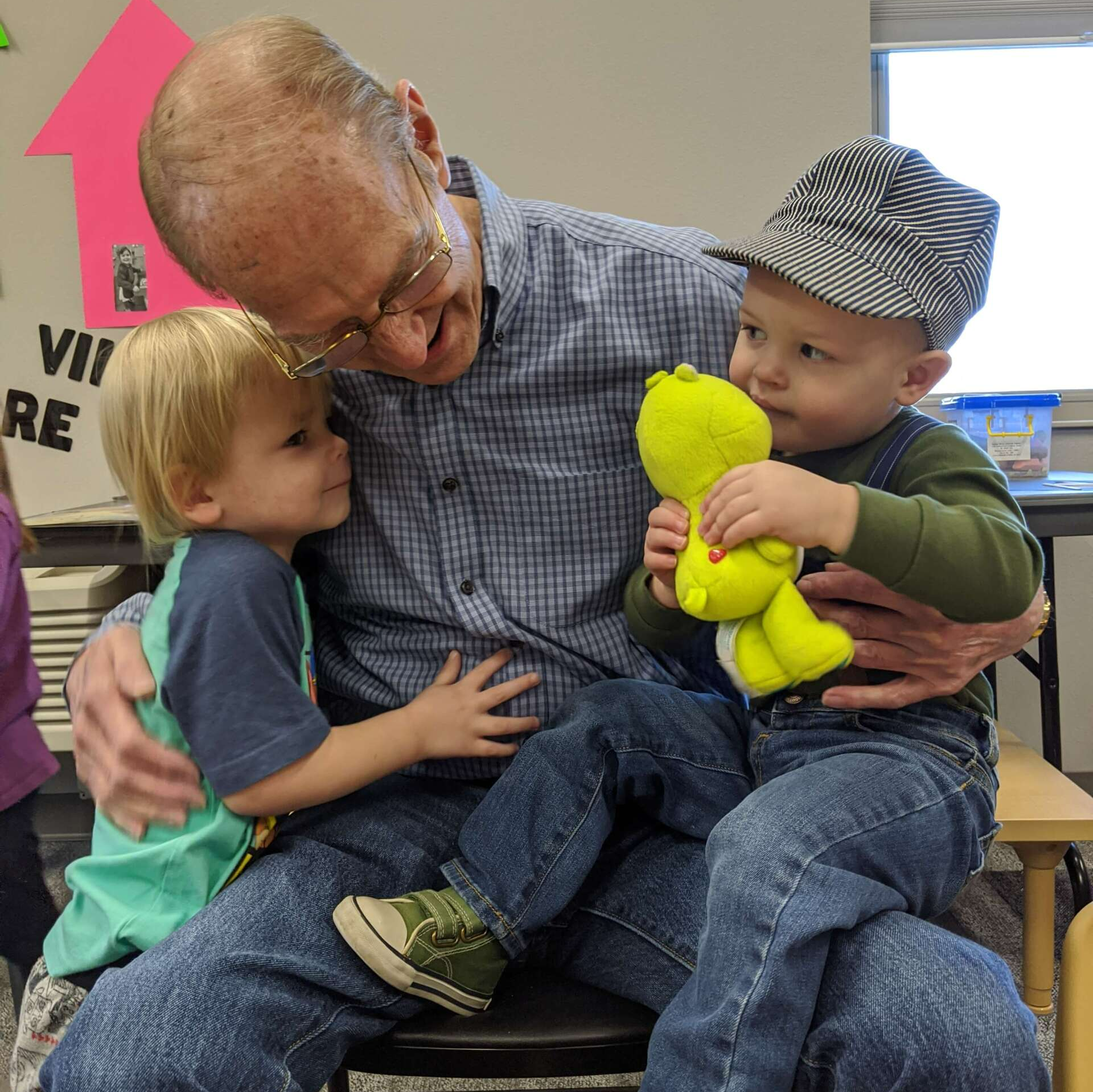 Senior man hugging and holding two boys at It Takes a Village Childcare Center