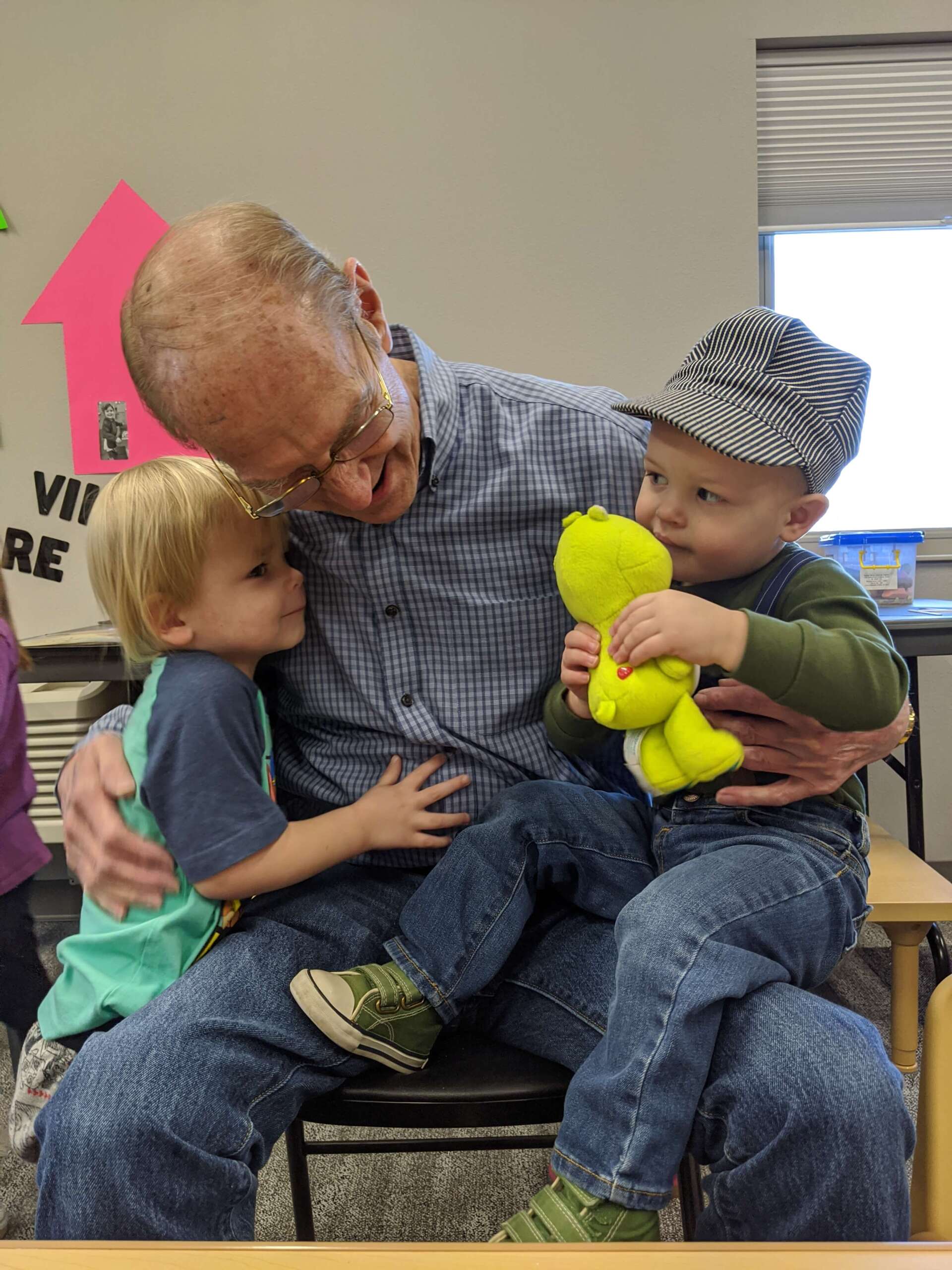 senior resident hugging and playing alongside kids at It Takes a Village Childcare