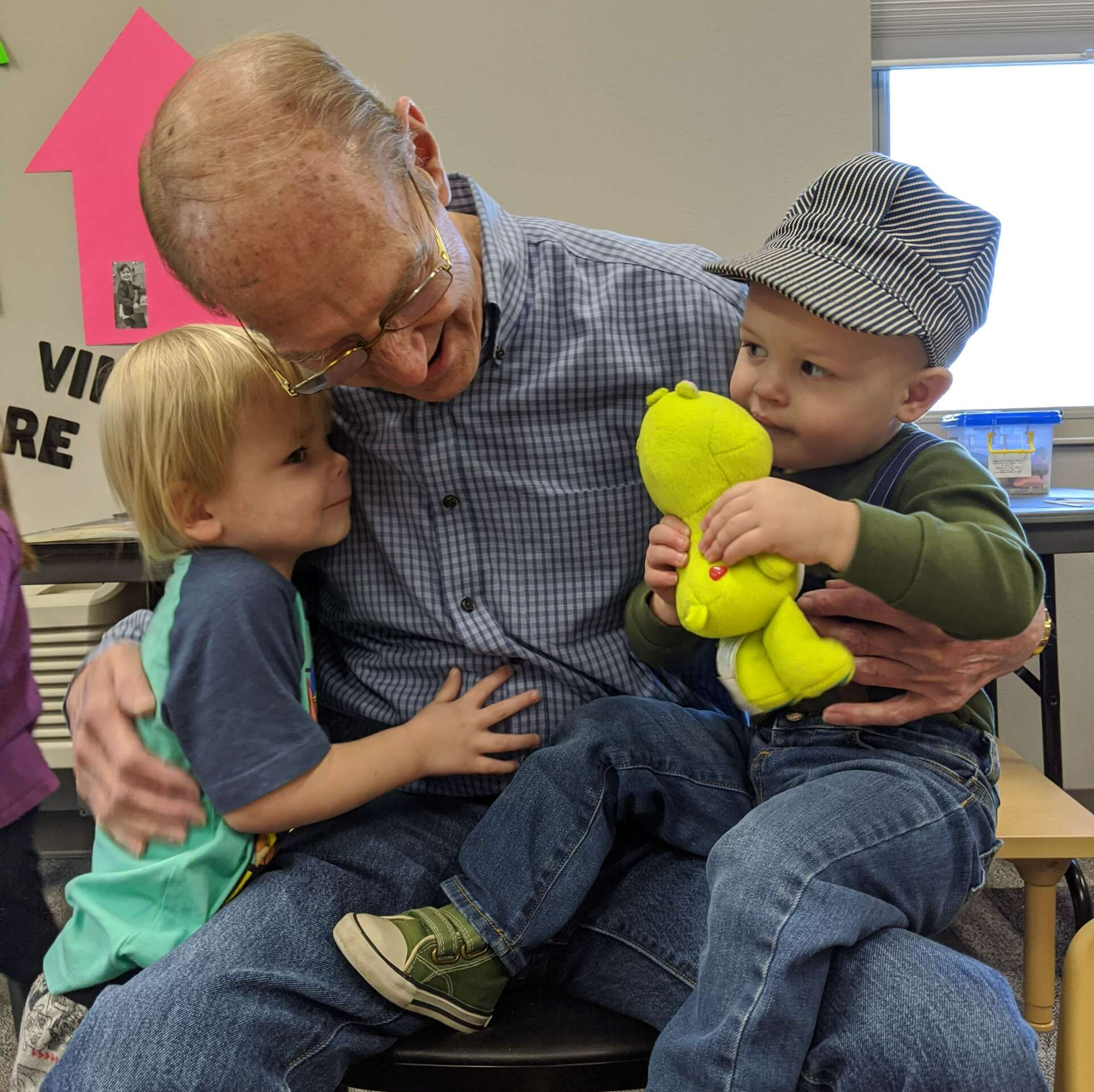Senior man hugging and holding two boys at It Takes a Village Childcare Center