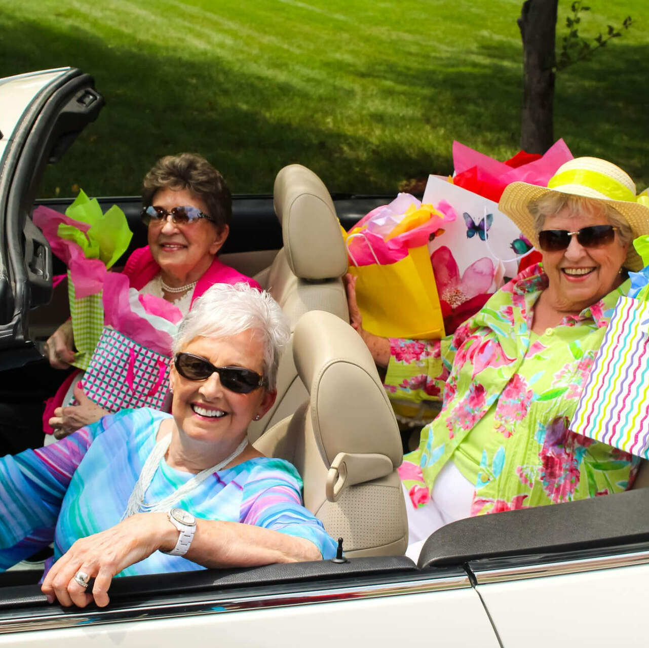active seniors driving around the community in a convertible after shopping