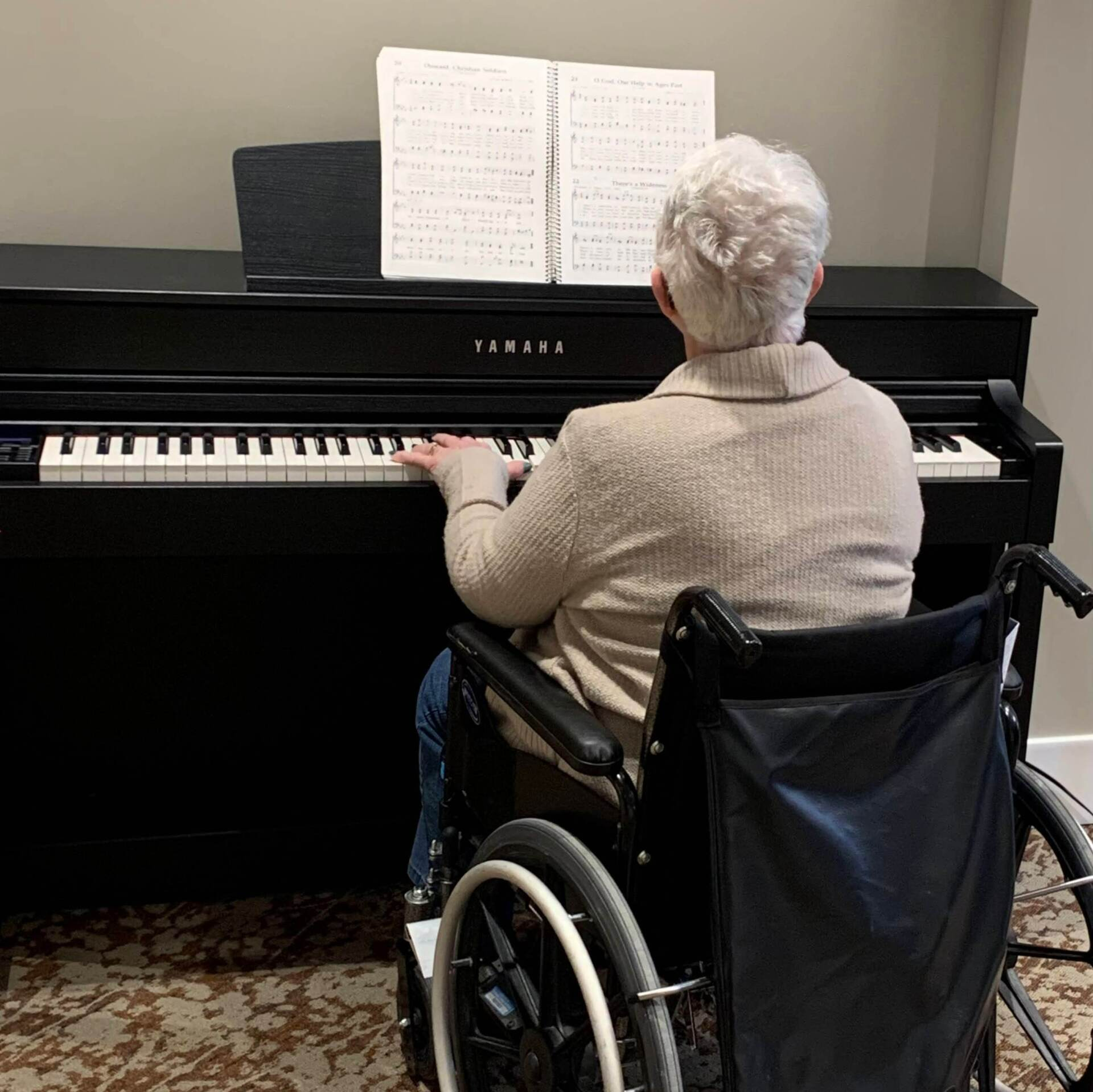 elderly resident reading music notes and playing the piano