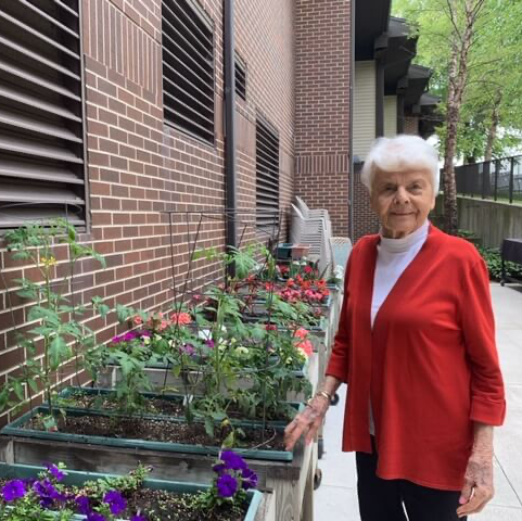 lady standing next to bed of flowers at assisted living residence